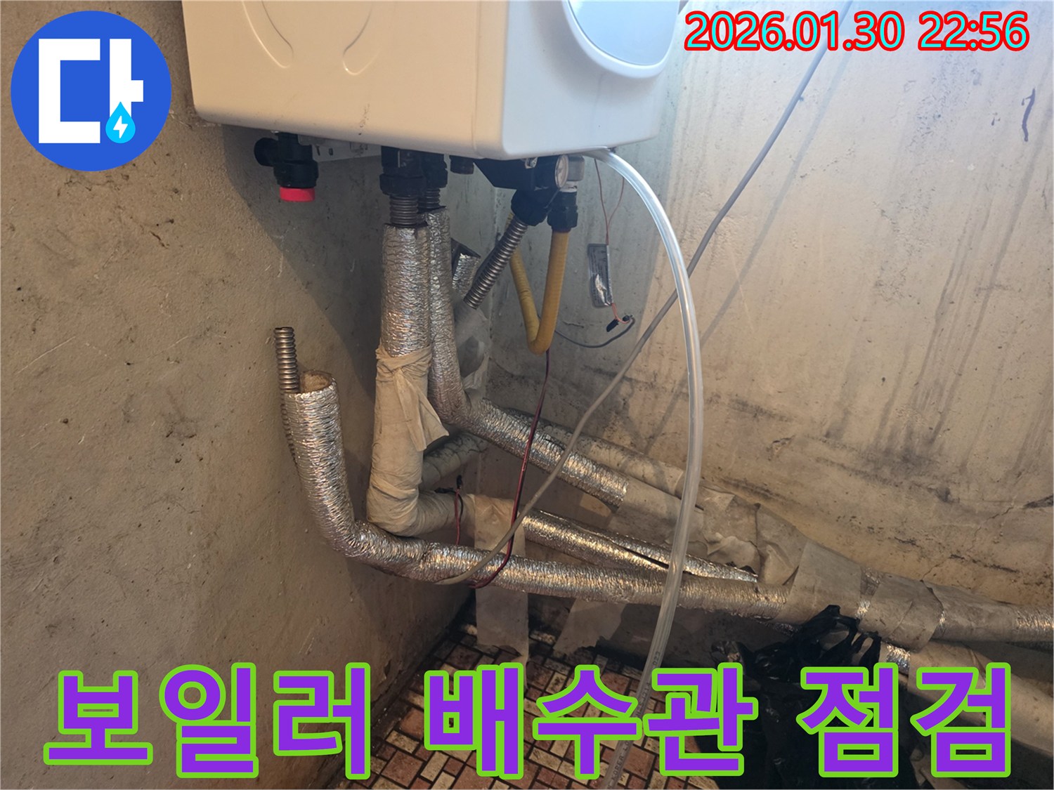 보일러 하단에 연결된 배수관 주변에서-누수가 의심되어-정밀 점검이 필요한 상황을 보여줍니다.