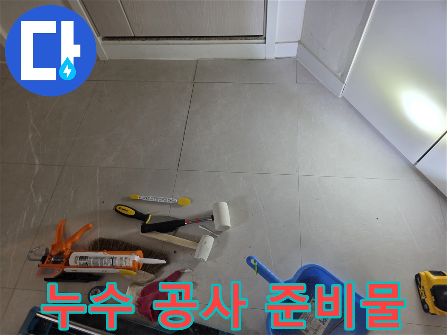 누수 보수 작업을 위해 바닥에 준비된 실리콘 건과 청소 도구들