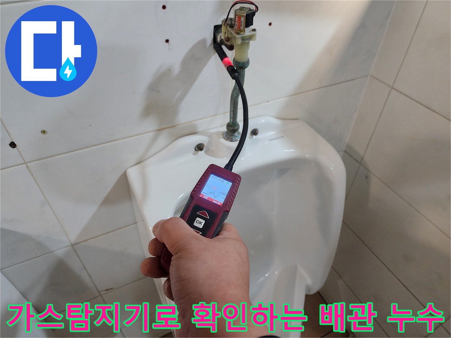 화장실 벽면 배관 부근에서 가스 탐지기를 사용하여 누수 지점을 정밀하게 추적하는 모습입니다.