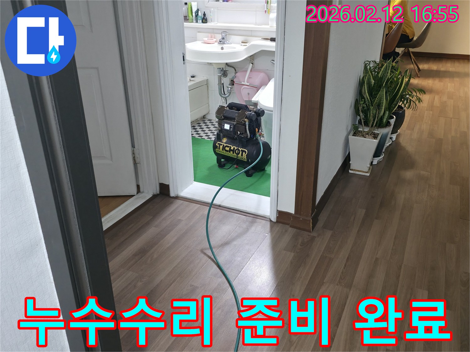 욕실 문간에-설치된 누수-탐지 장비와-연결된 호스가-바닥을 지나-누수수리를-위한-정밀 탐지-준비 과정