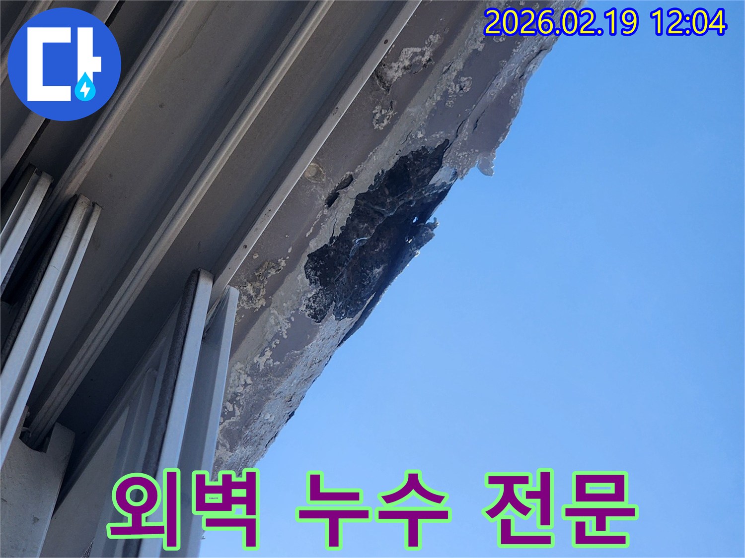 푸른 하늘과 대비되는-오래된 건물 외벽의-심각한 누수 손상으로 인한-표면 부식 및 박리 현장을 보여주는 사진