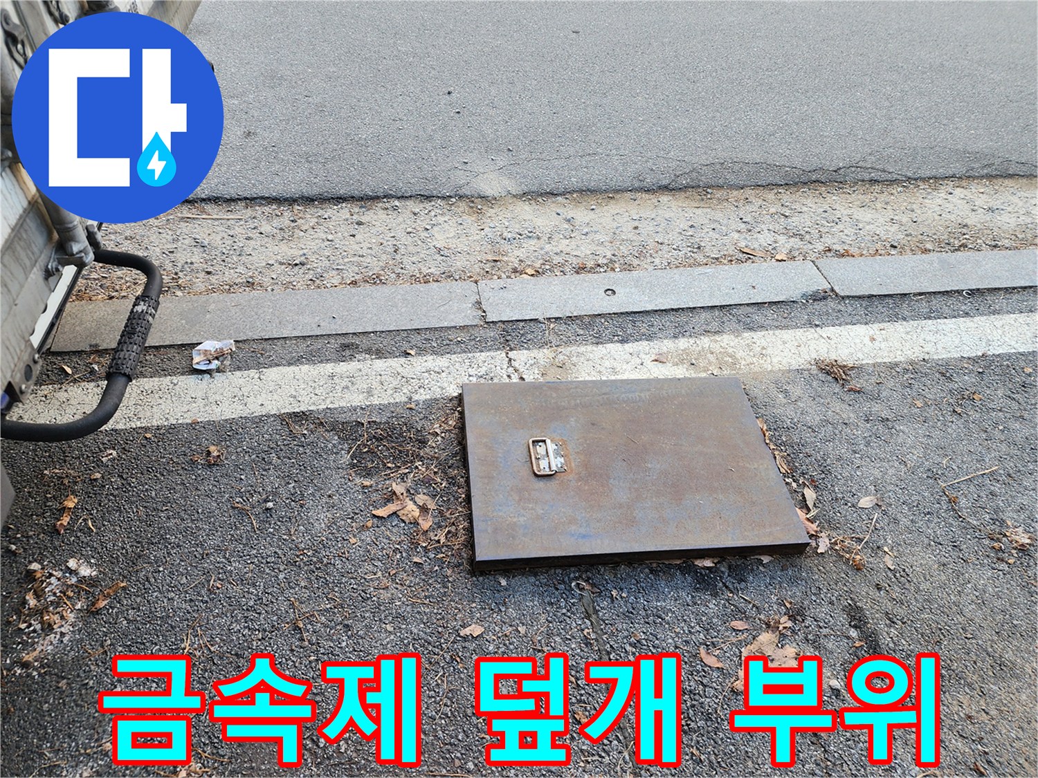 도로 경계석 옆에 설치된 금속 재질의 계량기 보호 덮개