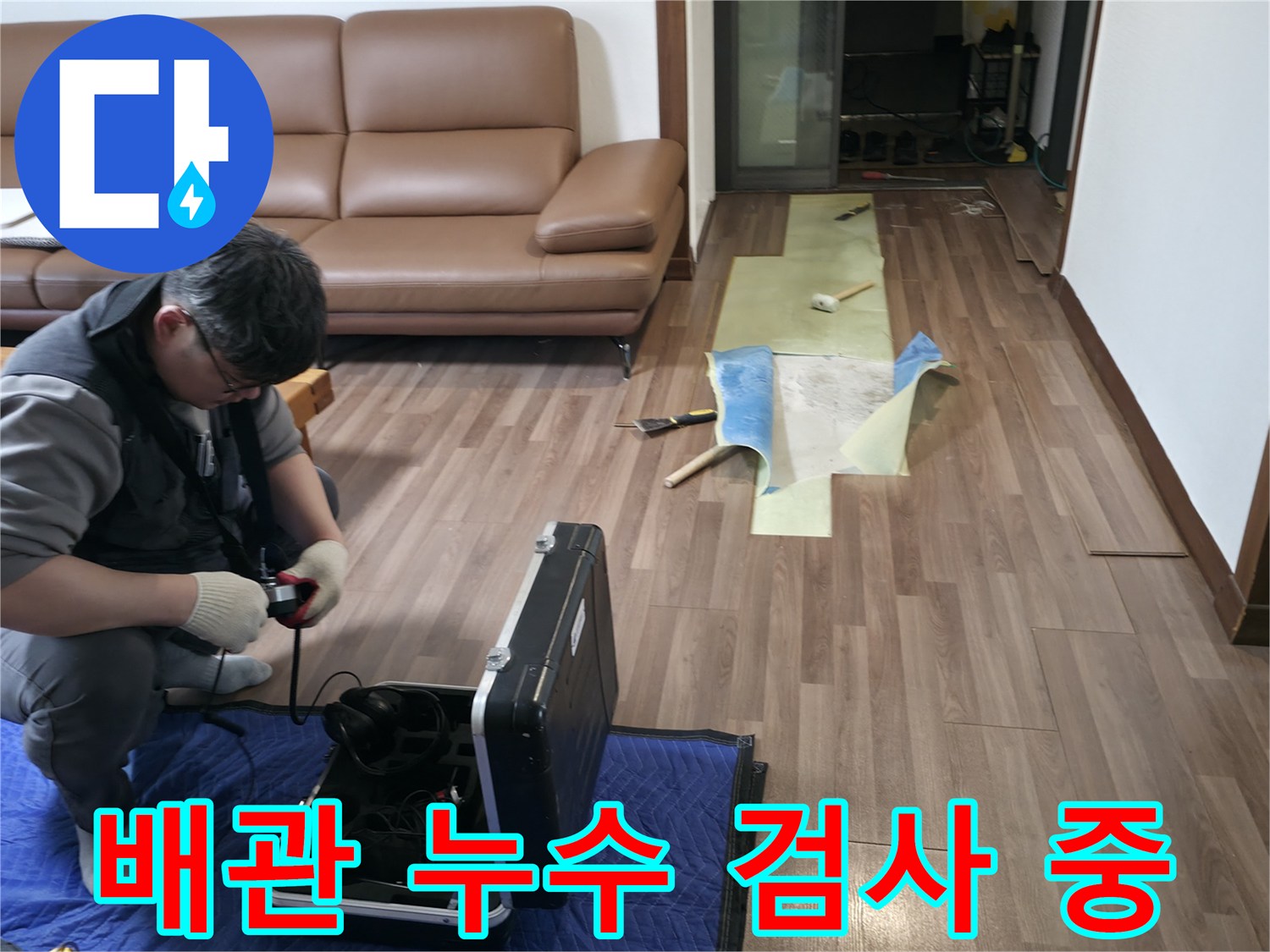 거실 바닥의 배관 문제를 확인하기 위해 가스 탐지기를 사용 중인 모습