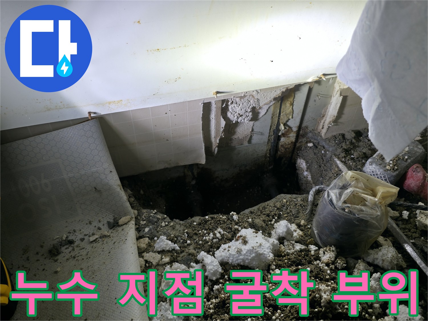 바닥을 파헤쳐 드러난 배관 주변의 습한 토양과 작업 도구