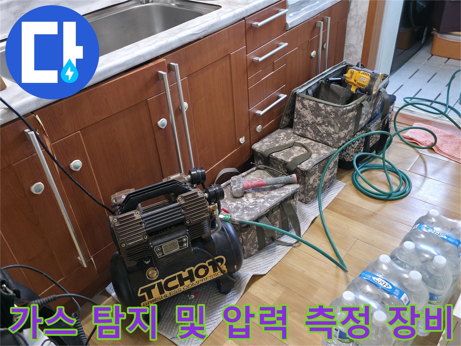 싱크대 하부장 근처에 배치된 누수 진단용 공압 장비와 가스 탐지 도구