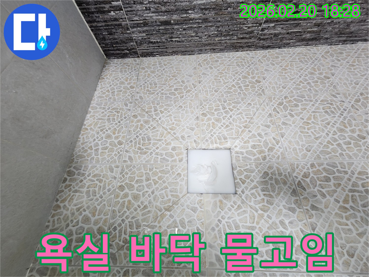 아파트 욕실 바닥 타일 위에 물이 고여-누수가 발생하고 있음을 보여주는 현장 사진