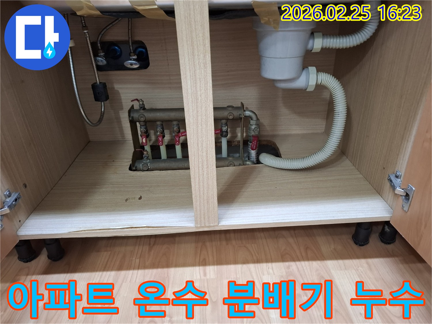 아파트 싱크대 하부장 내부에 설치된 온수 분배기에서 물이 새는 현장 사진입니다
