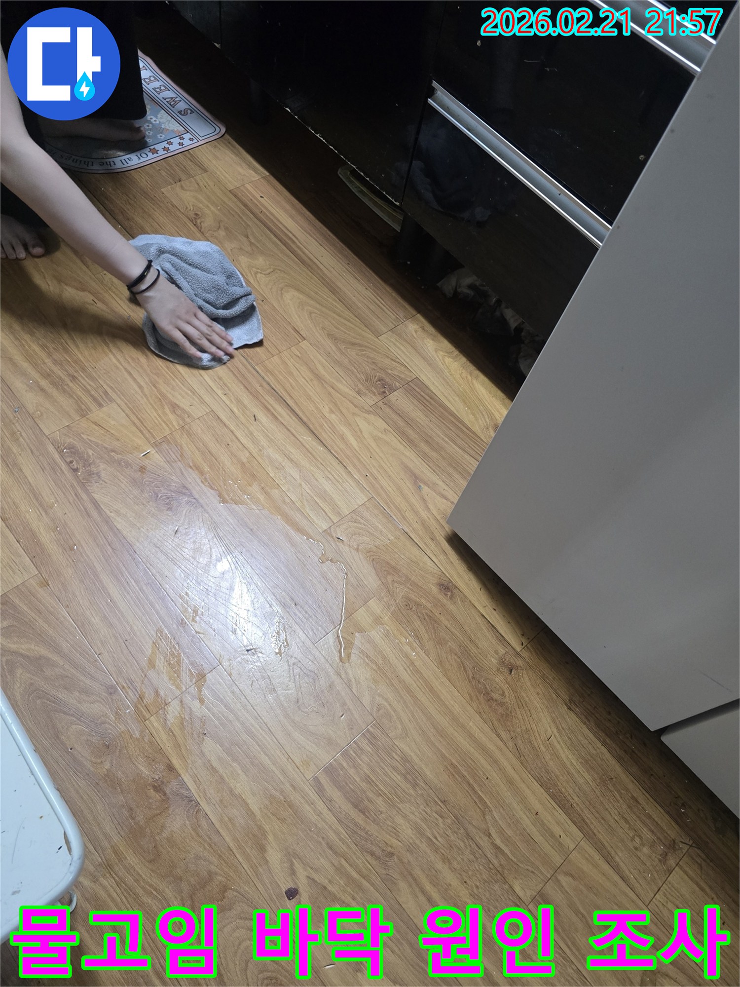 주택 바닥에-물이 고여있고-한 사람이-수건으로 물기를-닦아내고 있는-누수 현장 사진입니다.