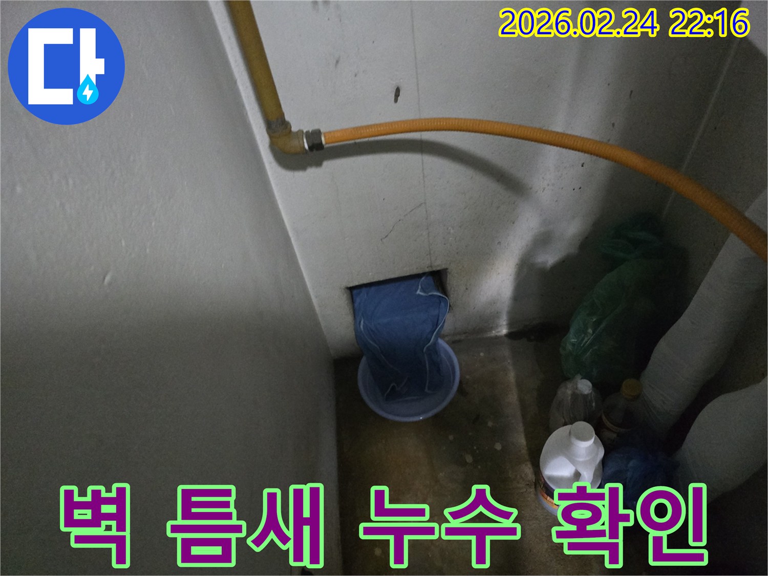 벽-하단부-구멍에서-물이-새어-나와-임시-용기에-받아지고-있는-누수-발생-장면