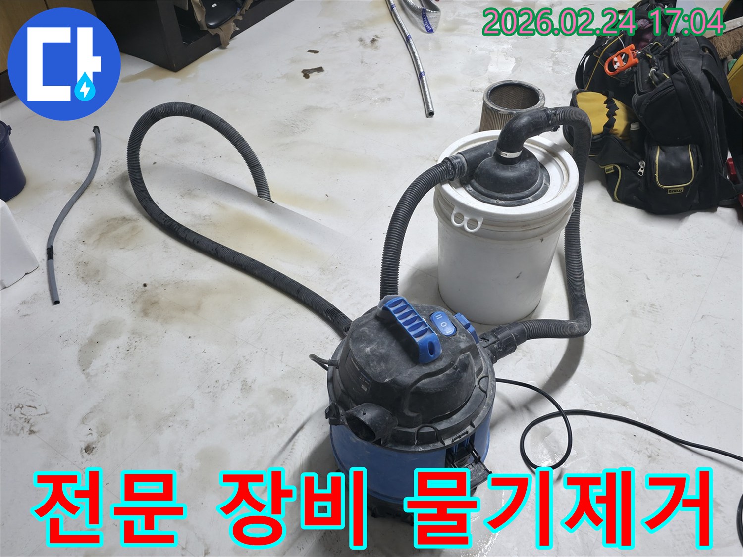 누수 현장에서 전문 습식 청소기와 보조 장비를 사용하여 물기를 제거하는 모습