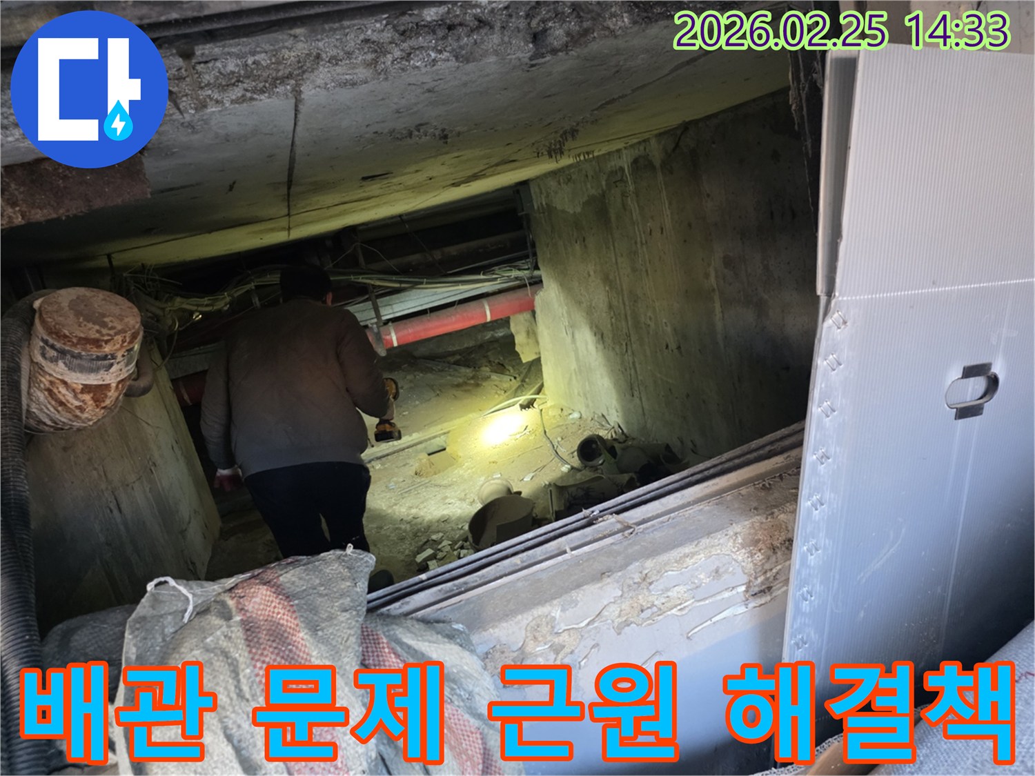 누수 전문 엔지니어가-어둡고 좁은 공간에서-손전등을 비춰가며-배관 문제의 근원적인 원인을-찾아내어 해결책을 제시하는 모습입니다.