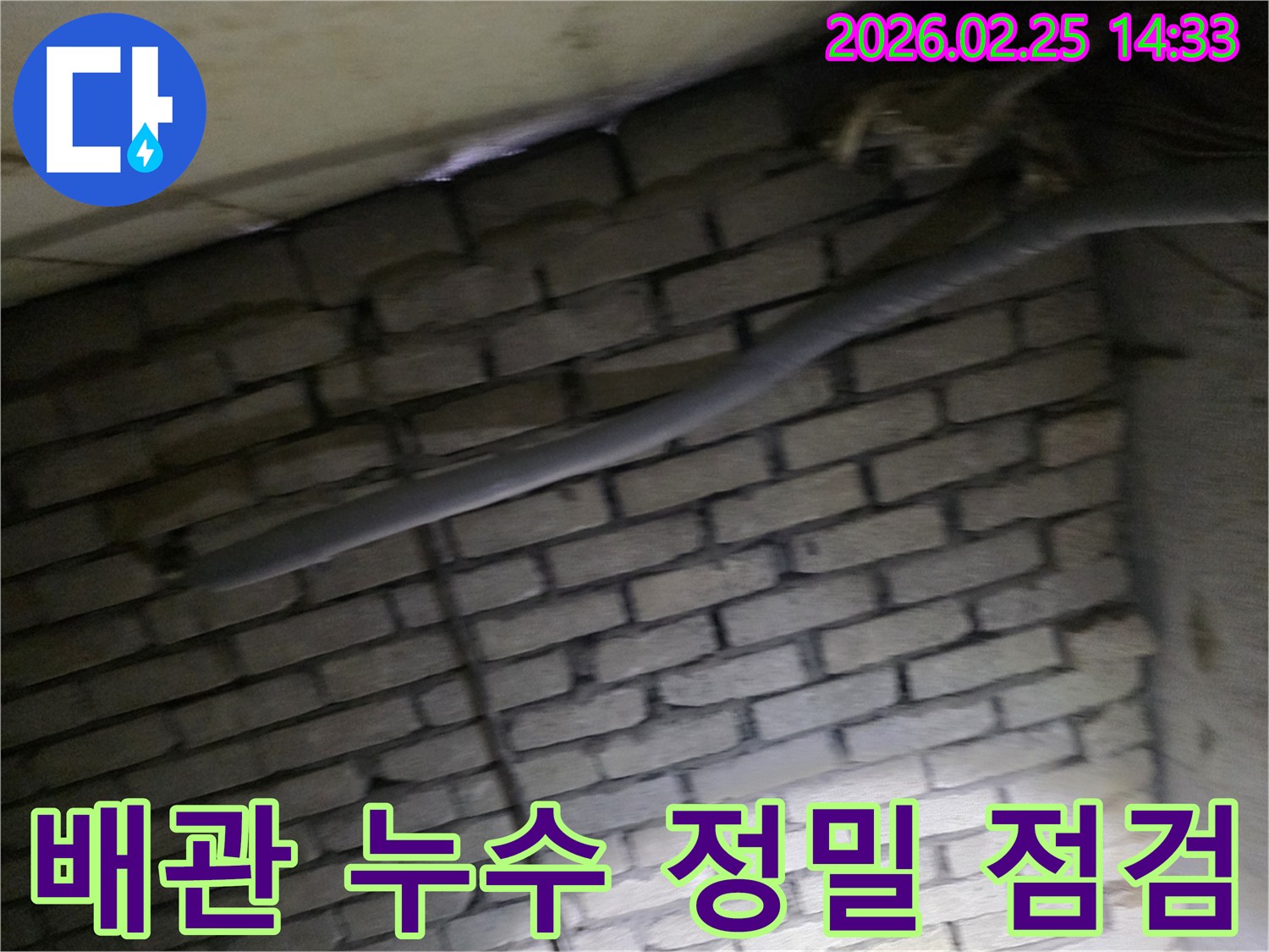 어두운 벽돌 벽면을 배경으로-단열된 배관과 함께-누수 여부를 정밀하게-점검하는 현장 모습입니다.