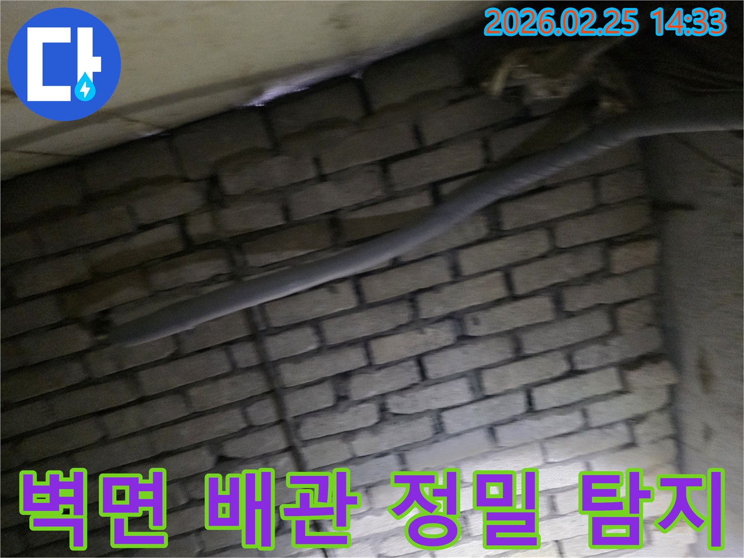어두운 벽돌 벽면을 배경으로-단열된 배관과 함께-누수 여부를 확인하기 위해-정밀하게 검사되는 현장 모습입니다.
