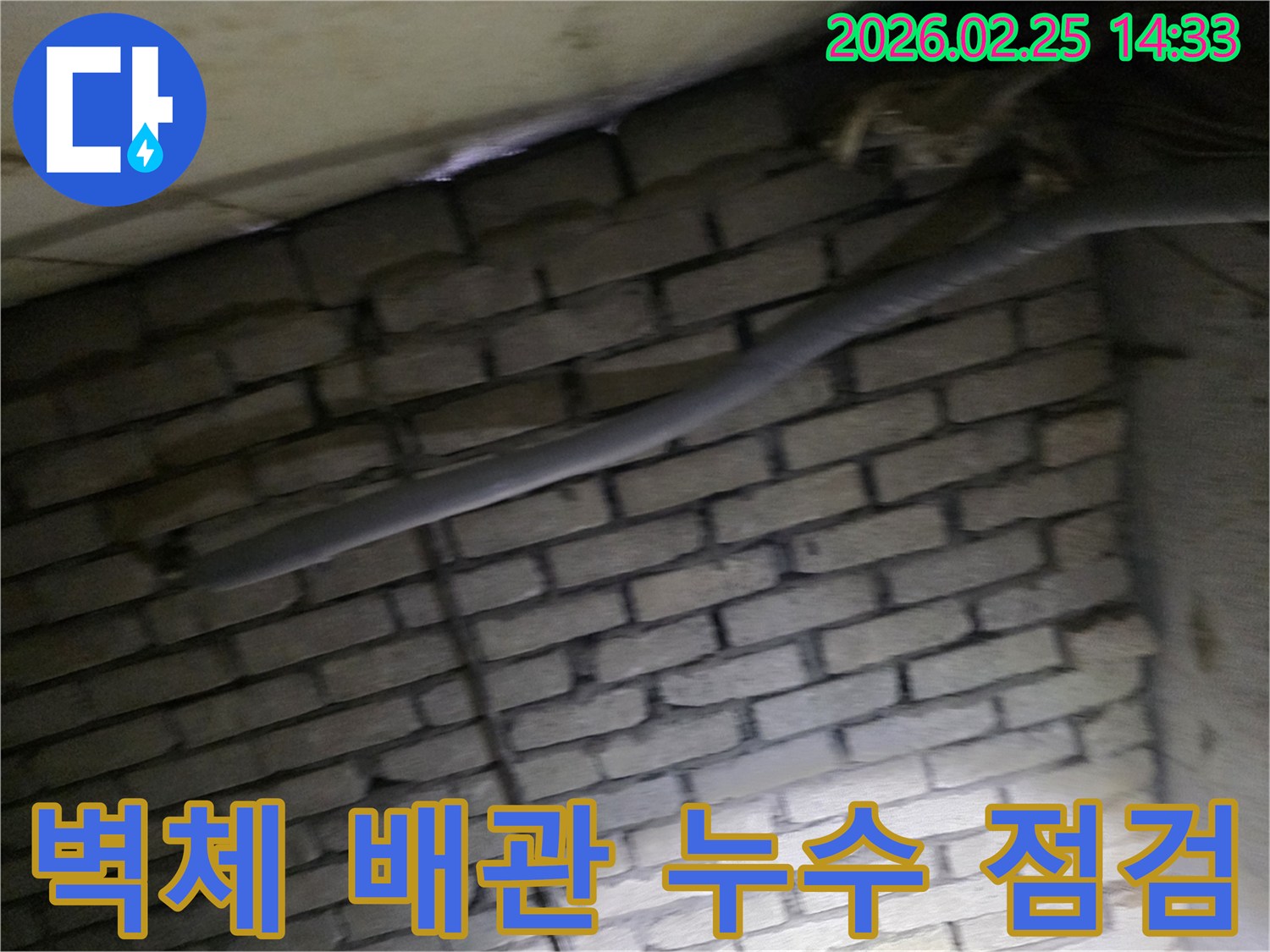 어두운 벽돌 벽면을 배경으로-단열된 배관과 함께-누수 여부를 확인하기 위해-정밀하게 검사되는 현장 모습입니다.