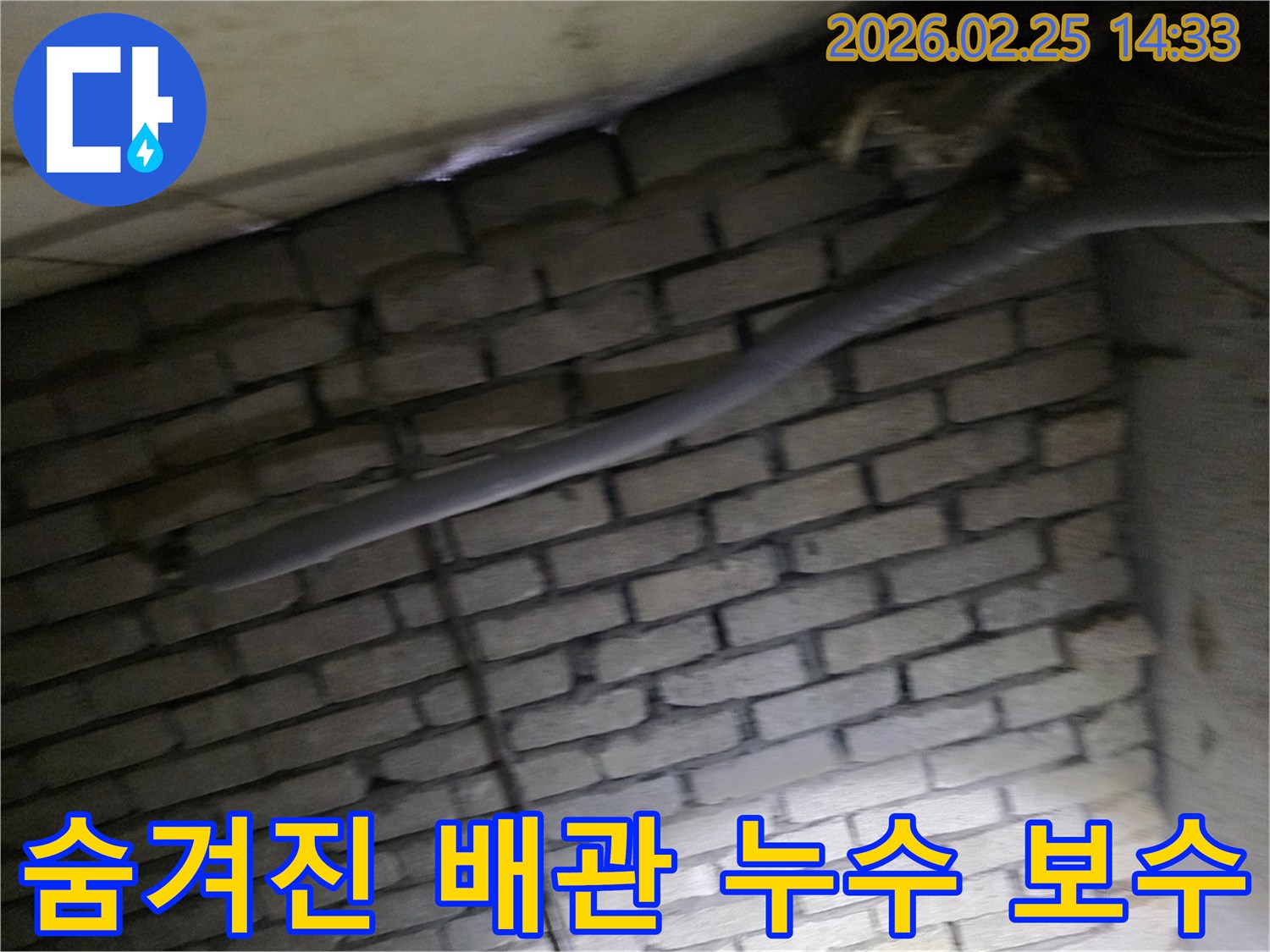어두운 벽돌 벽면을 배경으로-단열된 배관과 함께-숨겨진 누수 지점을 보수하기 위해-정밀하게 검사되는 현장 모습입니다.