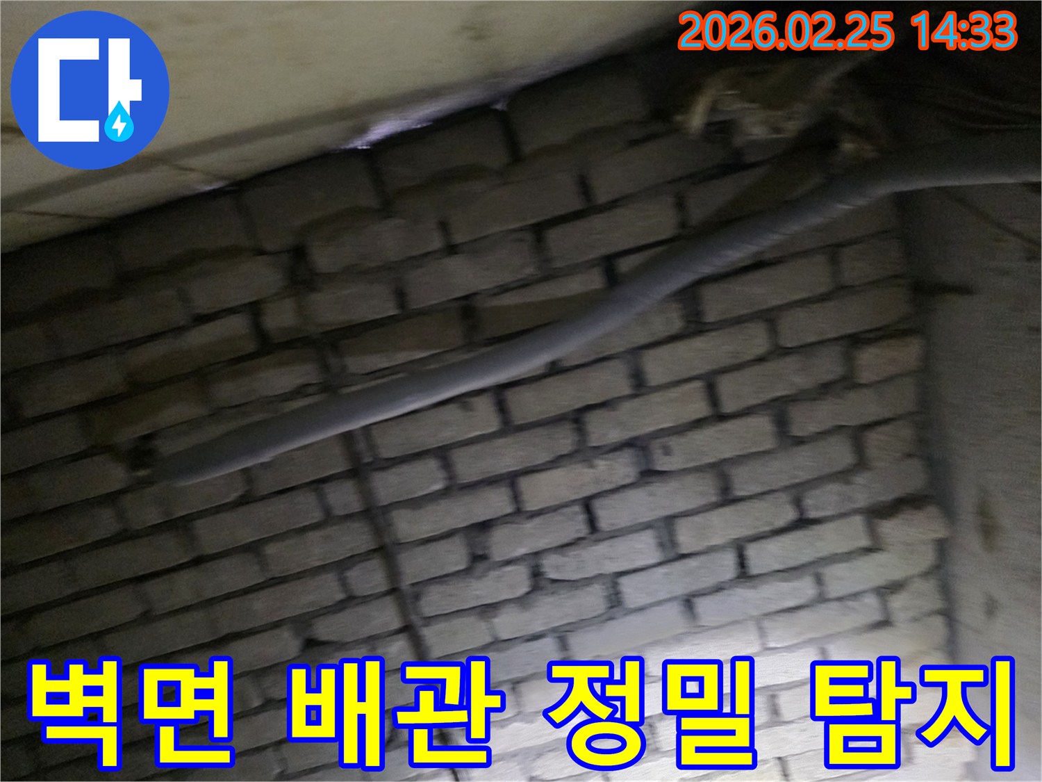 어두운 벽돌 벽면을 배경으로-단열재로 감싸인 배관에서-누수 여부를 정밀하게-탐지하는 현장 이미지입니다.