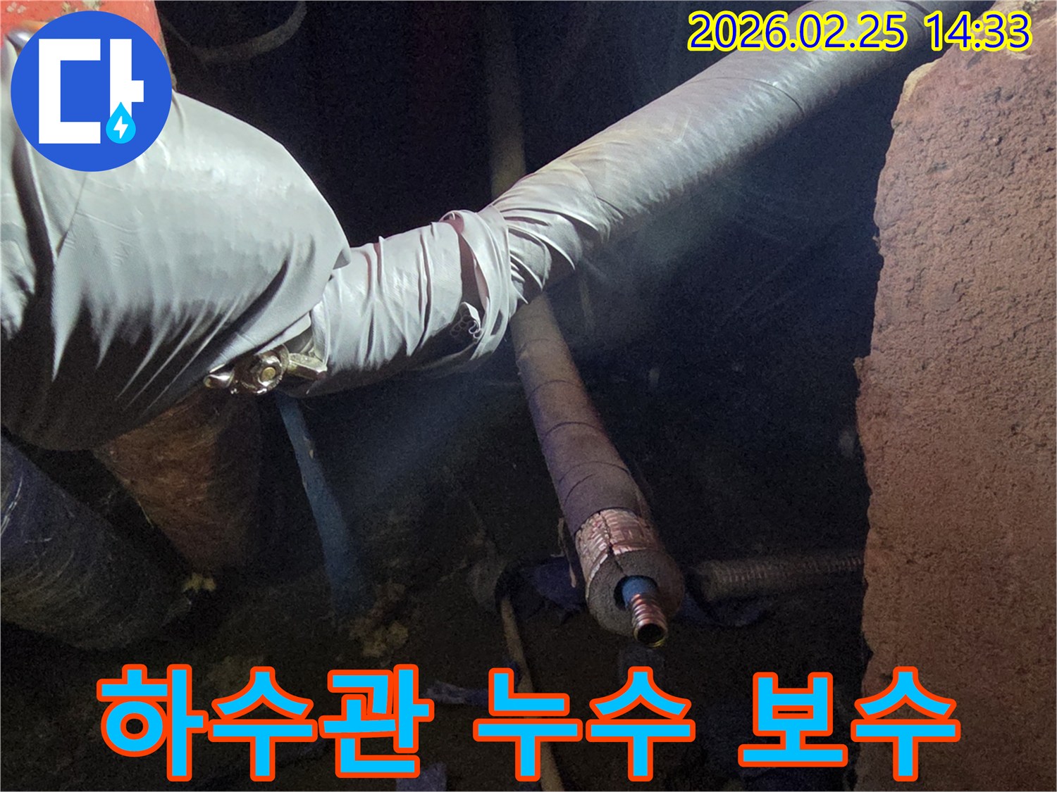 어두운 작업 공간에서-장갑을 낀 손이-손상된 하수관의-연결 부위를-세심하게 점검하며-수리 작업을-준비하는 모습입니다