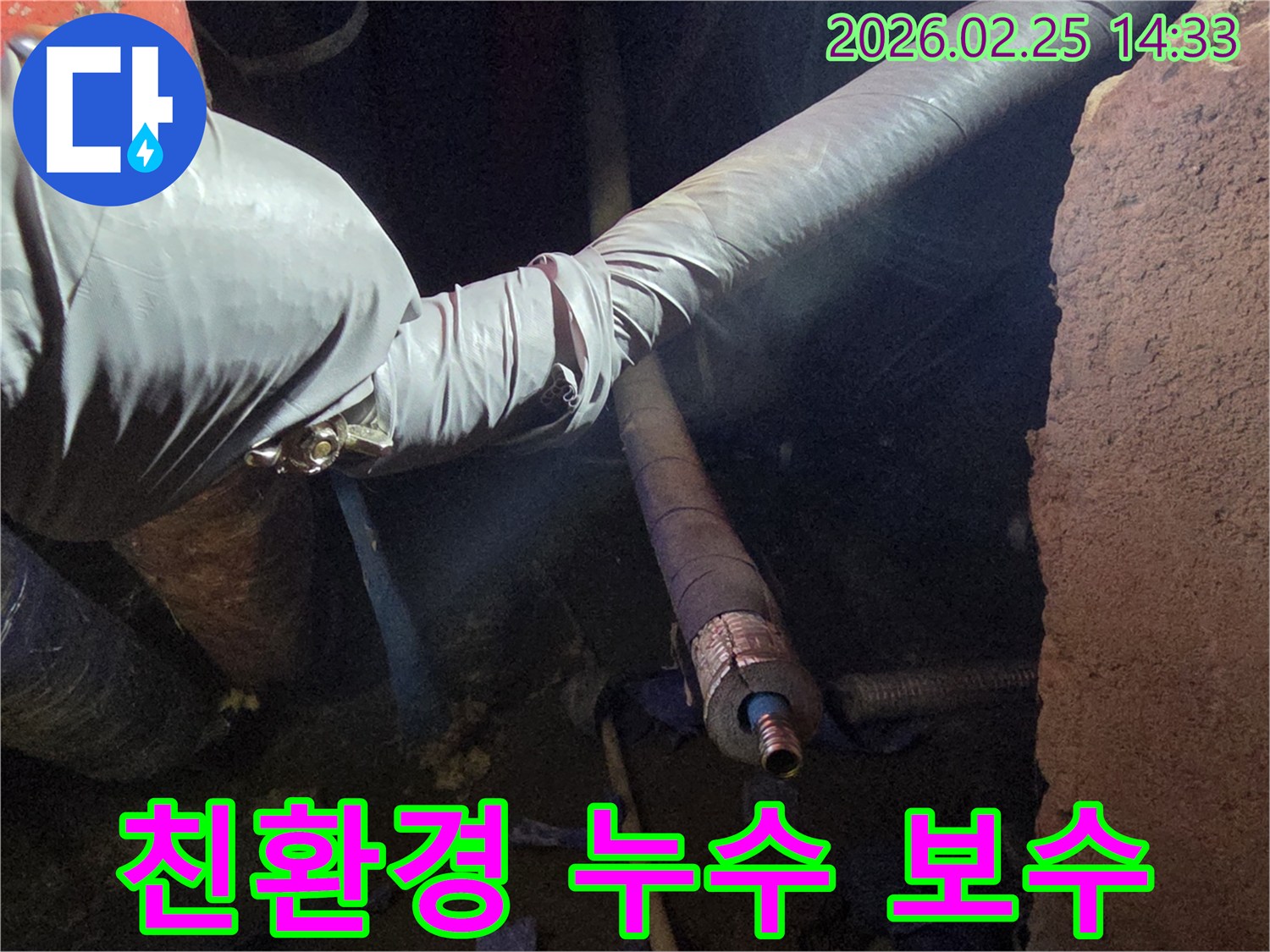 어두운 작업 공간에서-장갑을 낀 손이-친환경 자재를 사용하여-손상된 배관을-안전하게 보수하는-모습입니다