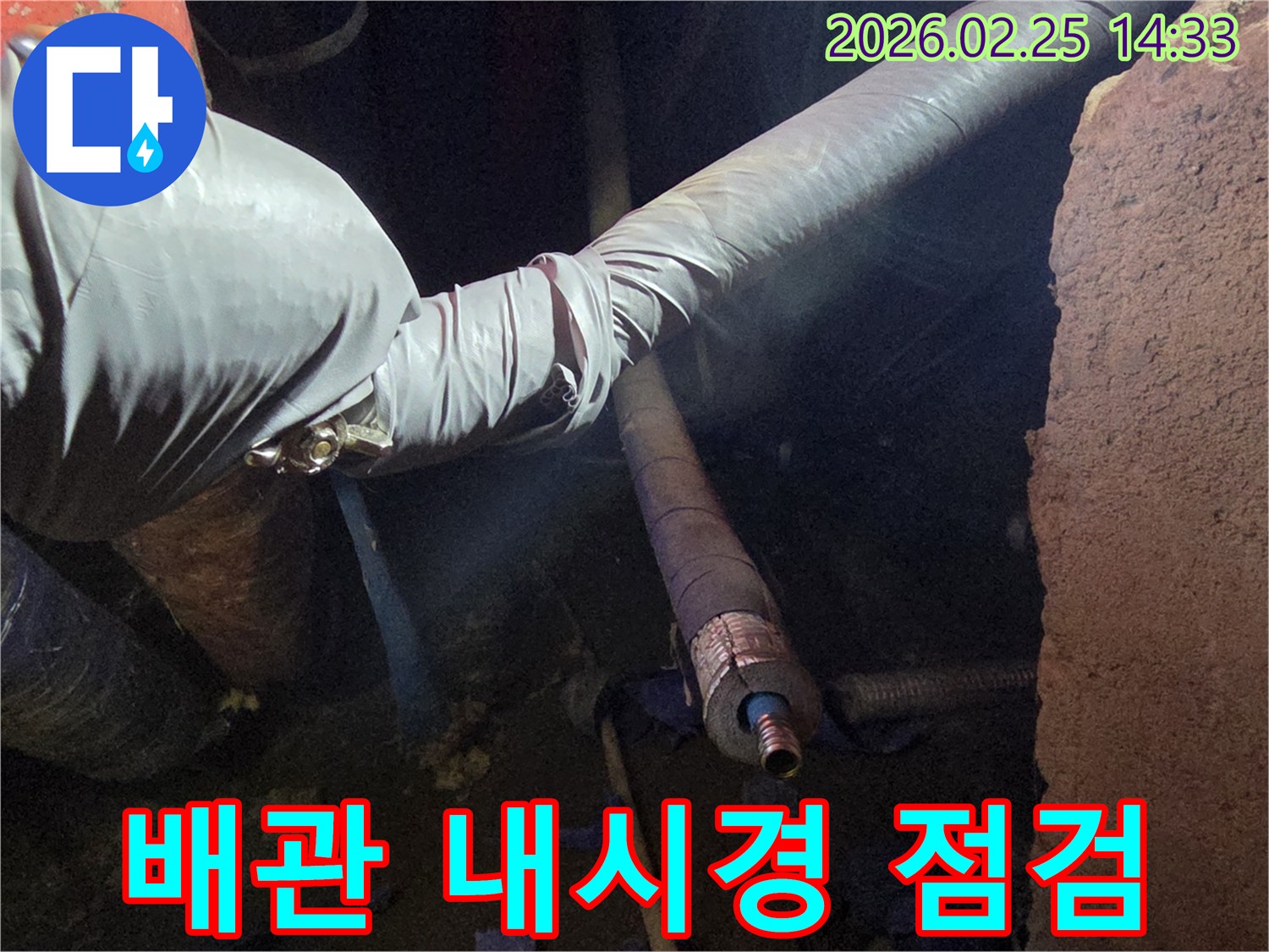 어두운 작업 환경에서-장갑을 낀 손이-내시경 카메라를-이용하여-배관 내부의-손상 여부를-정밀하게 점검하는-모습입니다