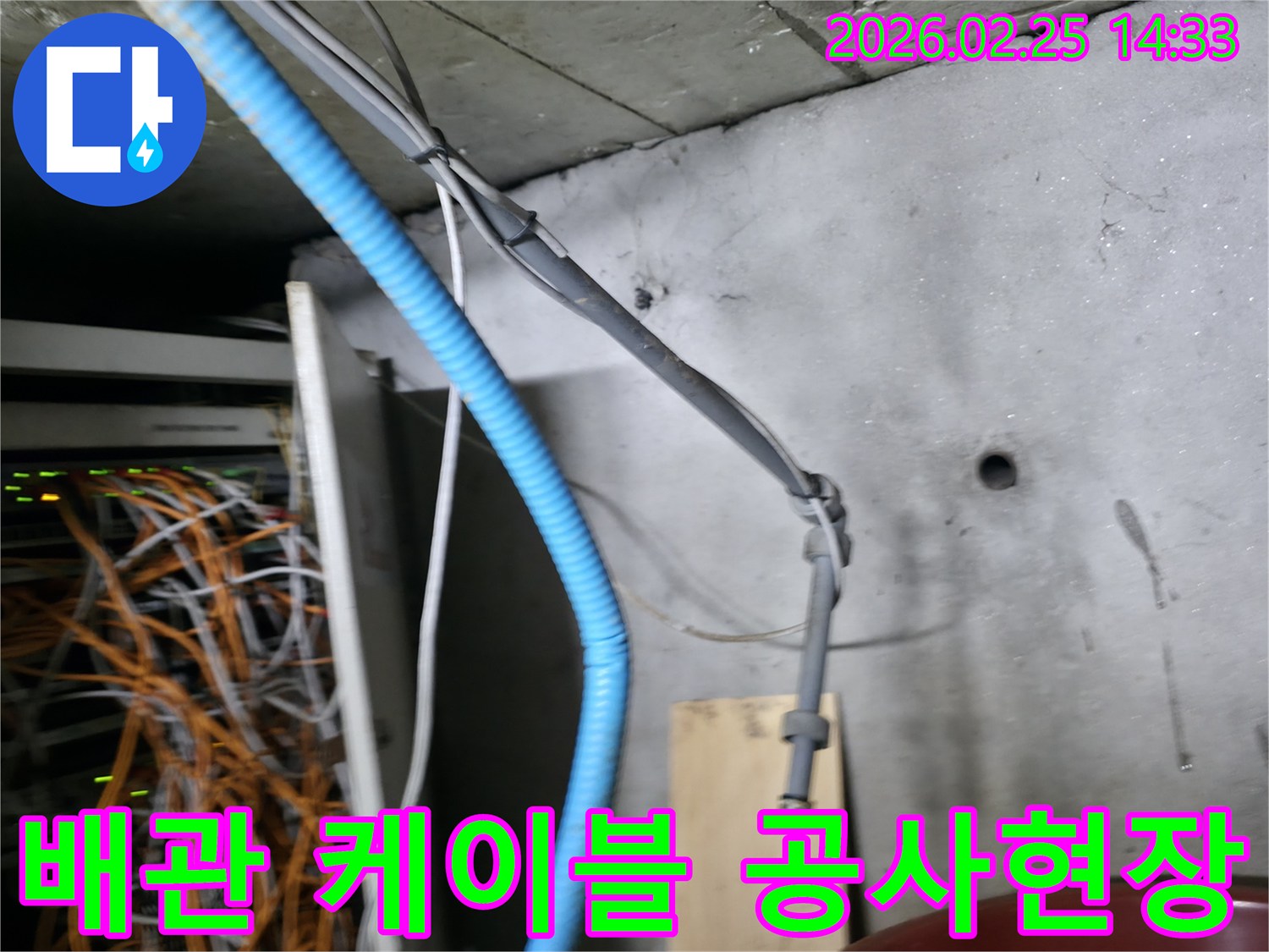 이 이미지는 누수 공사 현장에서-복잡하게 얽힌 배관과 케이블이-콘크리트 벽면을 따라 설치된 모습을 보여줍니다
