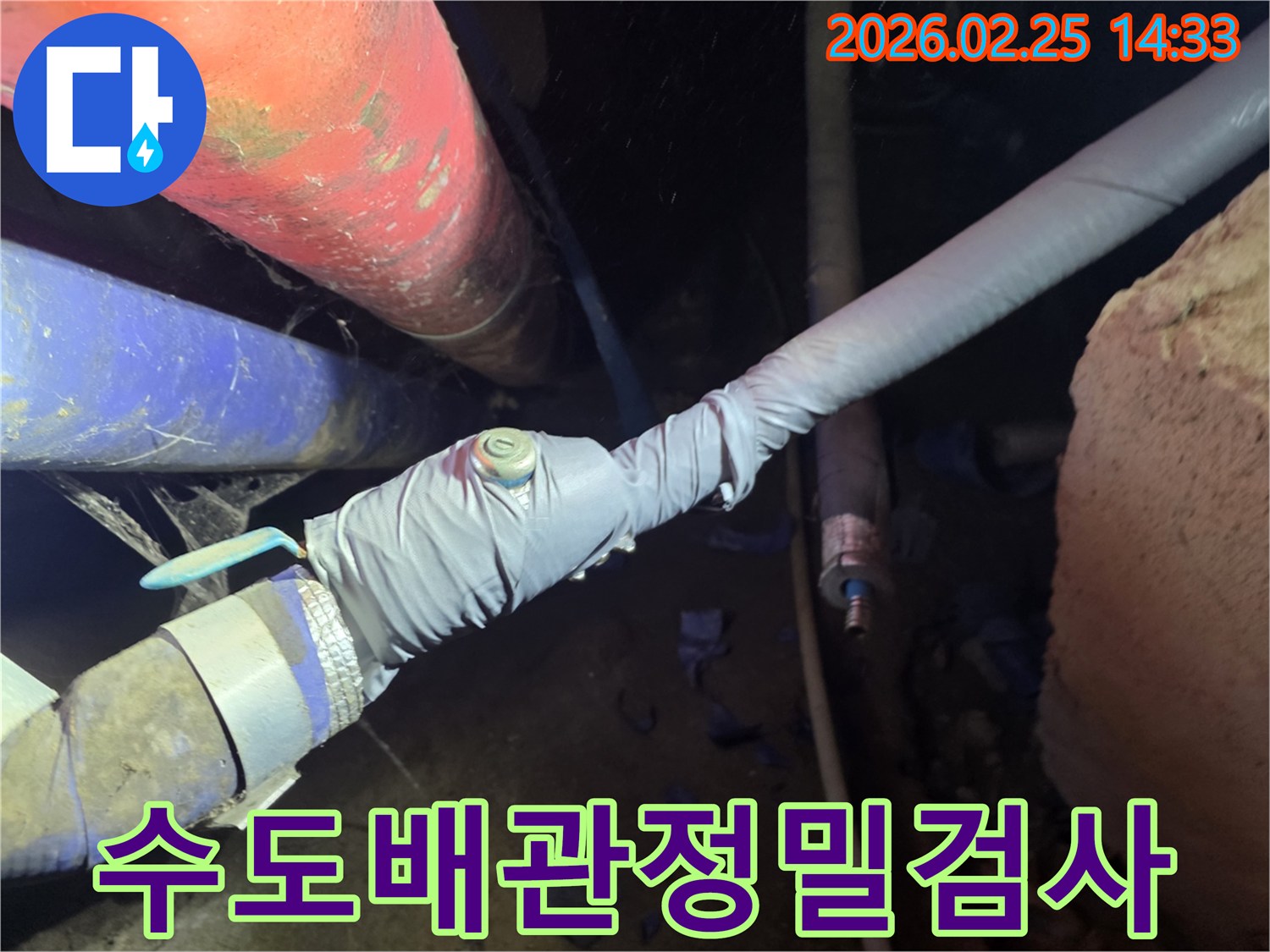 이 이미지는 누수 탐지를 위해 배관에 압력 측정 장비를 연결하는 전문 엔지니어의 모습을 보여줍니다-정확한 누수 지점을 찾기 위한 핵심 과정입니다