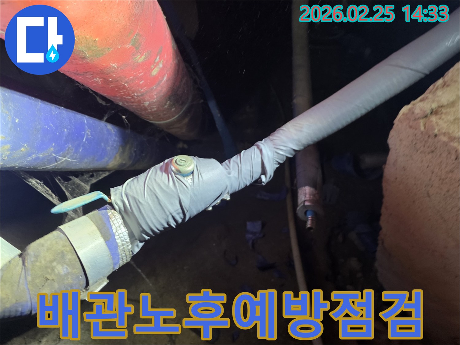 이 이미지는 누수 탐지를 위해 배관에 압력 측정 장비를 연결하는 전문 엔지니어의 모습을 보여줍니다-정확한 누수 지점을 찾기 위한 핵심 과정입니다