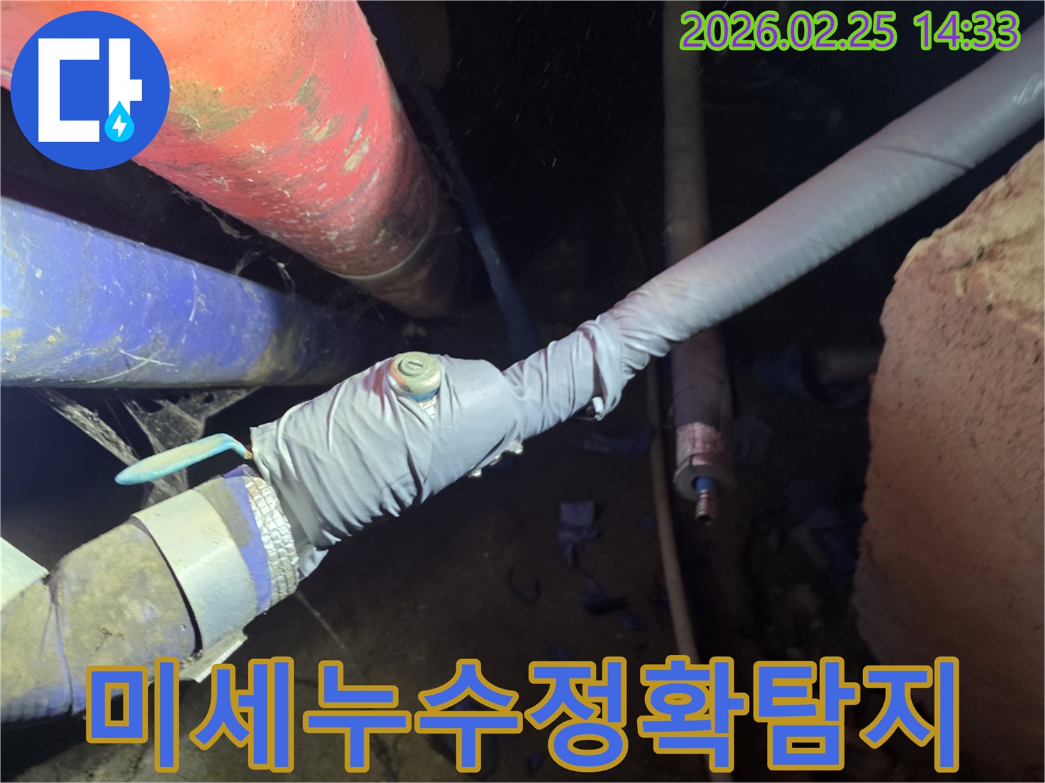 이 이미지는 누수 탐지를 위해 배관에 압력 측정 장비를 연결하는 전문 엔지니어의 모습을 보여줍니다-정확한 누수 지점을 찾기 위한 핵심 과정입니다