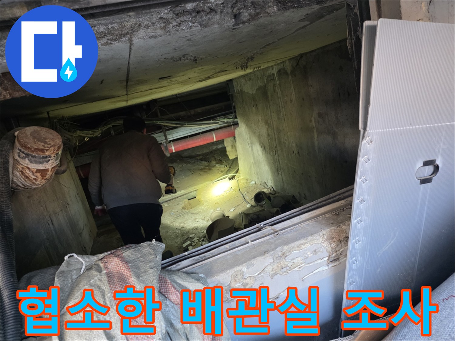 좁은 공간의 지하 배관실에서 배관 상태를 점검하고 있습니다.