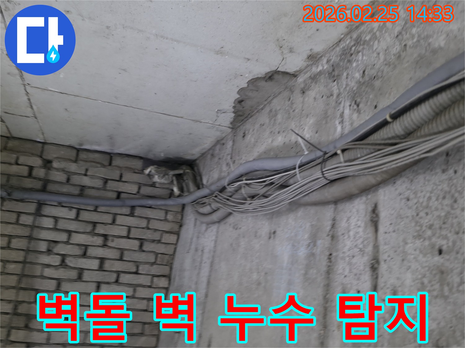 지하 공간의-콘크리트 벽과-벽돌 벽 사이에서-발생한 누수로 인한-심각한 물자국과-배관의 모습