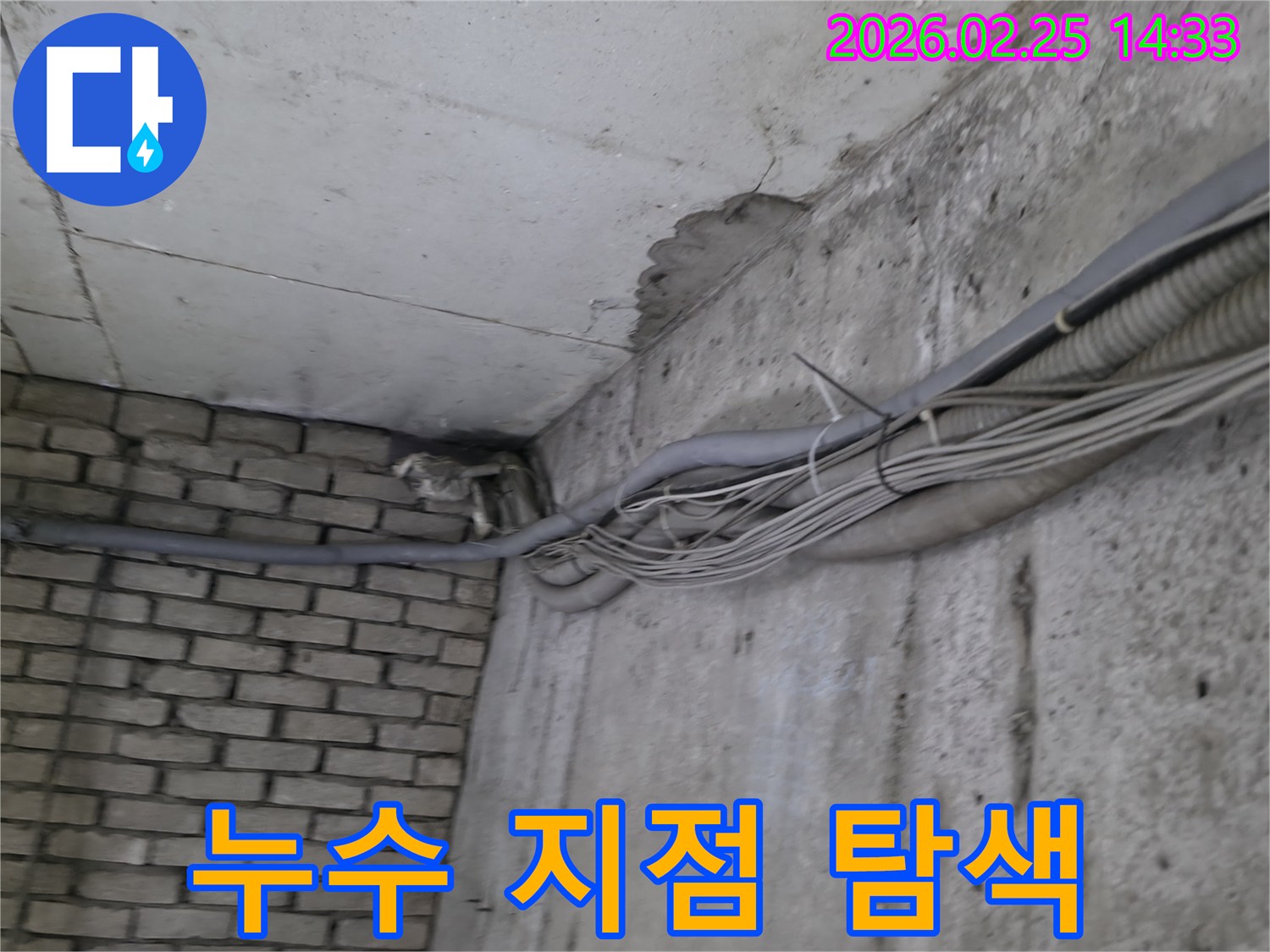 지하 벽면의-콘크리트와-벽돌 벽이 만나는-지점에서-발견된-오랜 누수로 인한-물자국과-주변의 복잡한 배관