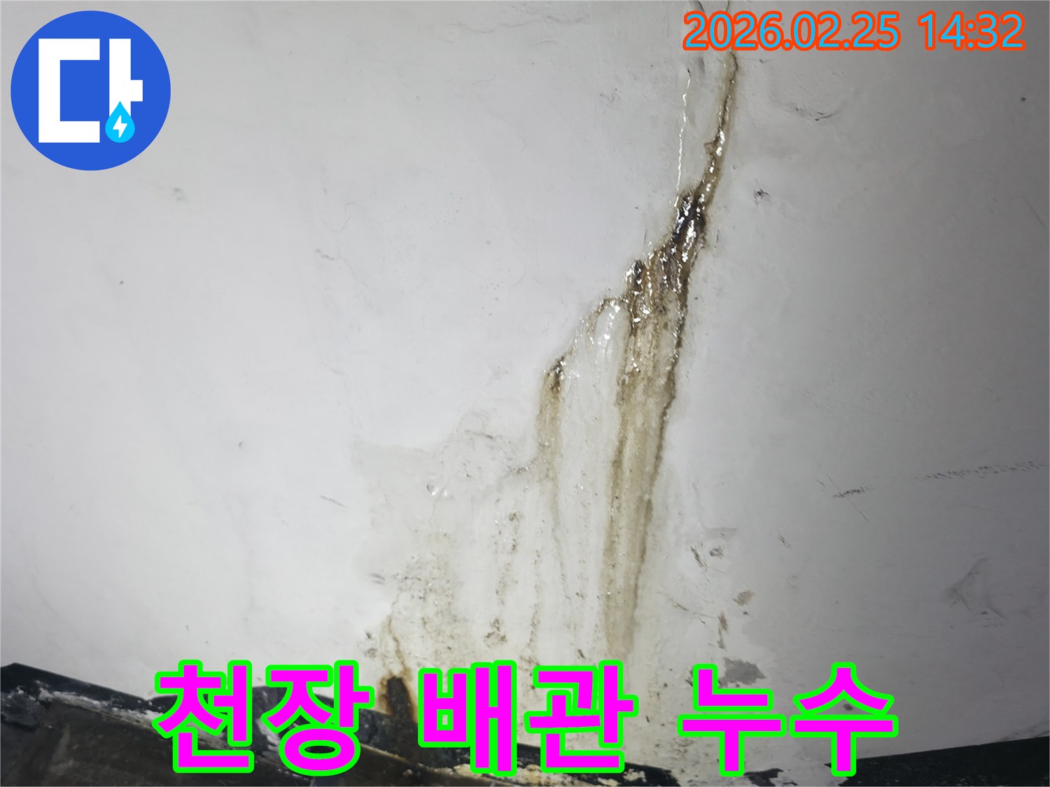 천장에서-수직으로-흘러내린-짙은 물자국을-보여주며-배관 누수를-시사하는-현장 사진