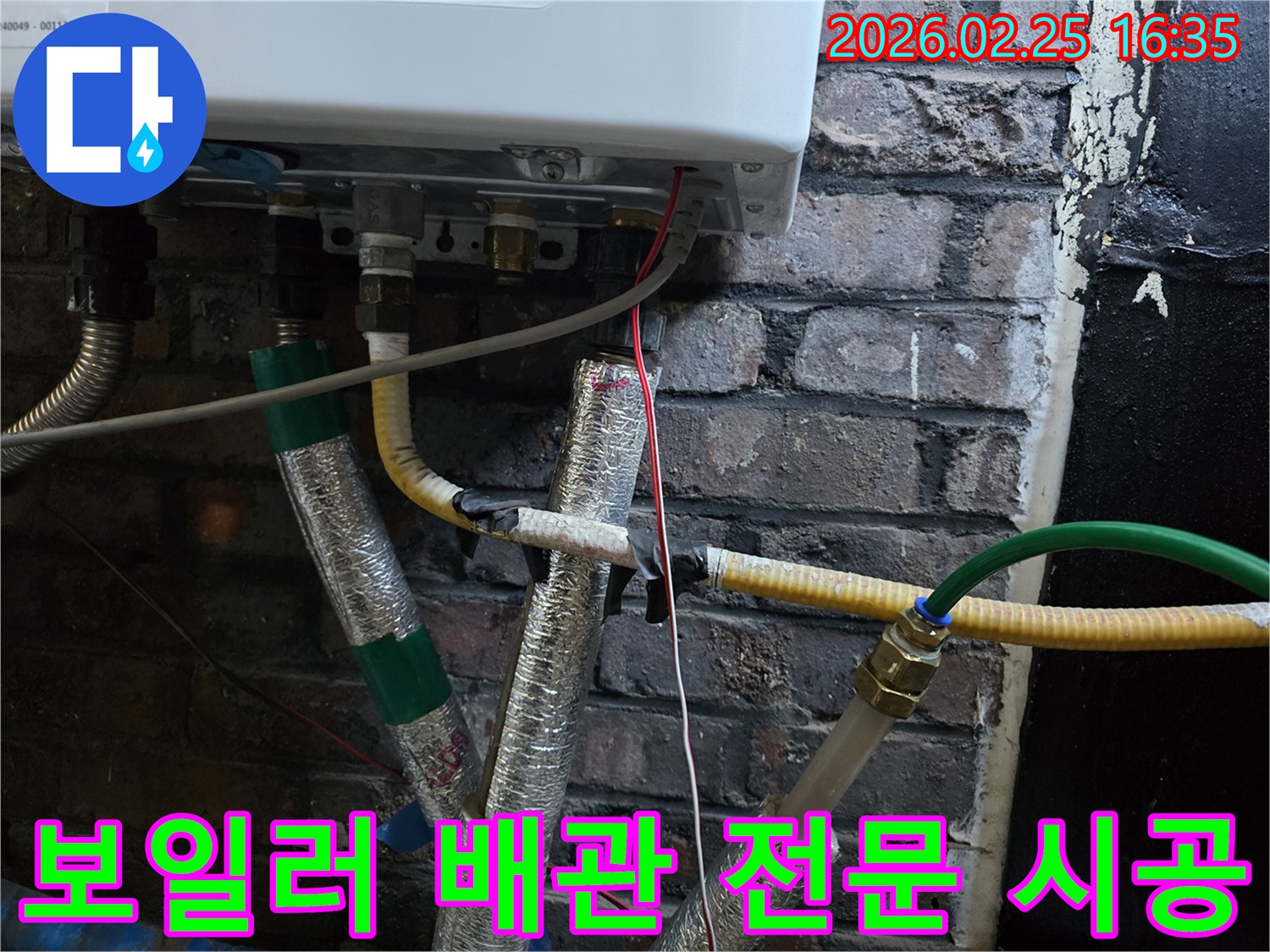 이 이미지는-벽에 설치된-보일러 하단부의-복잡한 배관 연결부와-전선-그리고-은색 단열재로-감싸진-파이프들을-보여주며-누수 전문 업체의-정밀한 시공이-필요함을-암시합니다.
