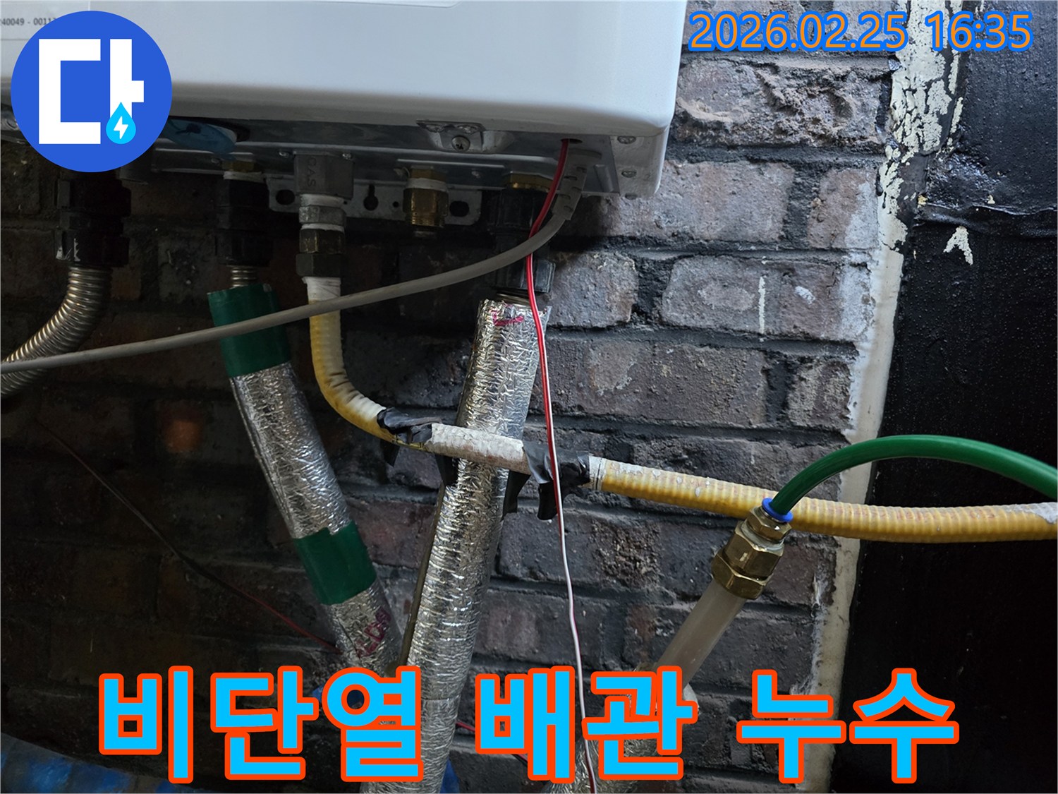 이 이미지는-보일러 하단부의-여러 배관 중-단열재로-감싸지지 않은-작은 흰색-또는-회색 배관을-보여주며-미세 누수나-결로 발생-가능성을-나타냅니다.