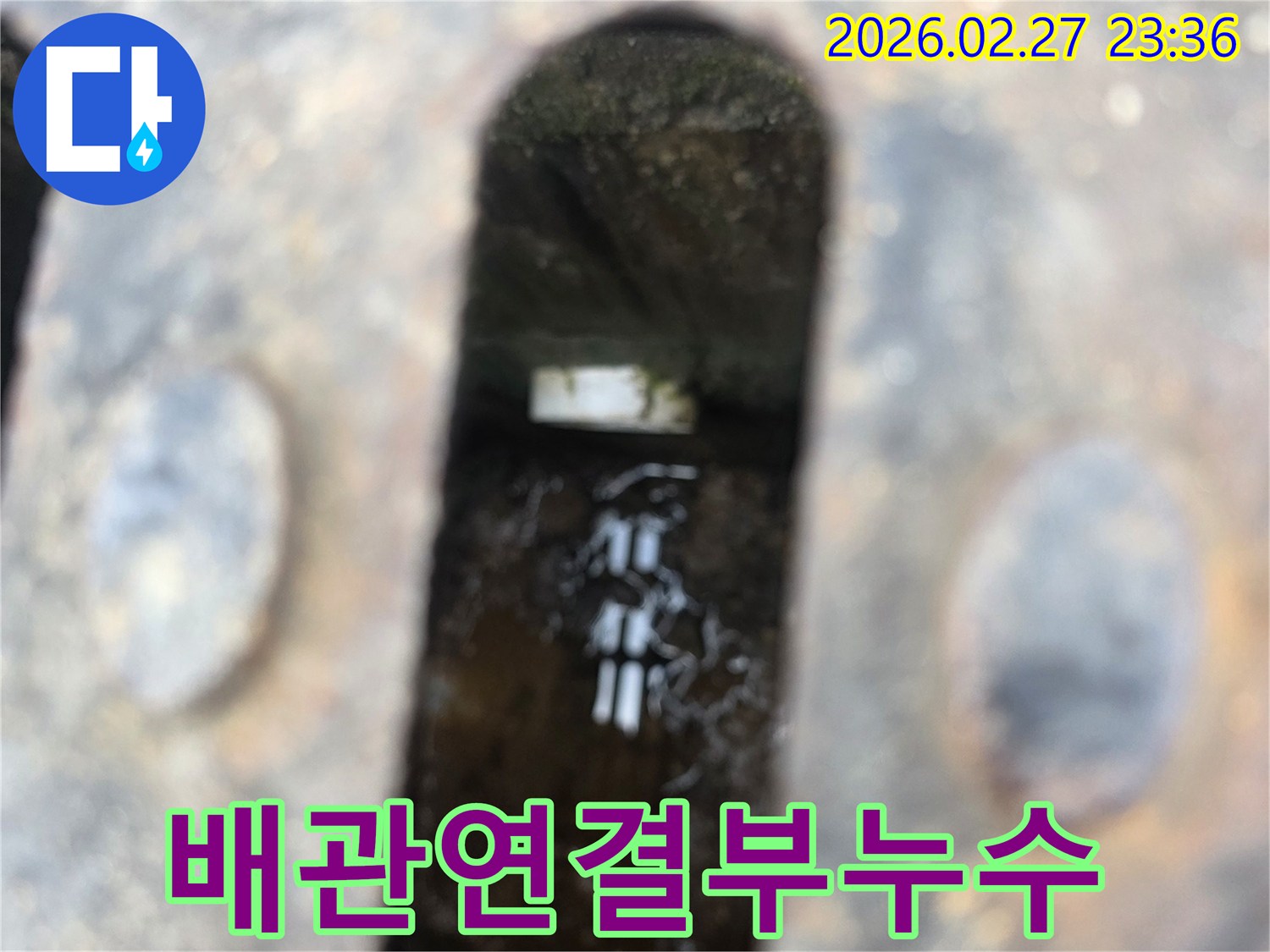 녹슨-철제-배수구-아래-고인-물과-물속에-잠긴-배관-연결부가-보이는-누수-현장