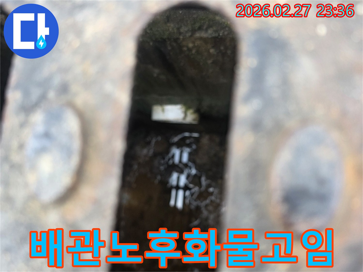 녹슨-철제-배수구-아래-고인-물과-물속에-잠긴-오래된-배관의-일부가-보이는-누수-현장