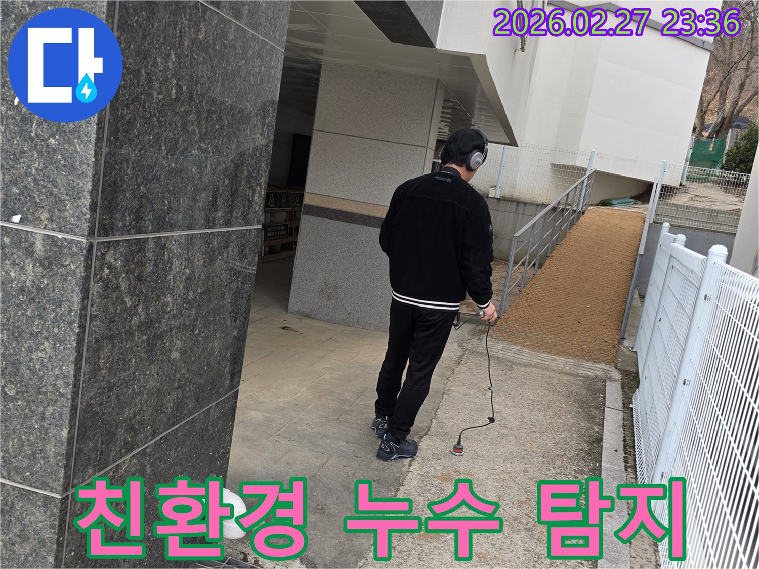 누수 엔지니어가-청음식 탐지 장비로-건물 외부의-누수 지점을 찾아내어-물 낭비를 막고-환경 보호에 기여하는 모습