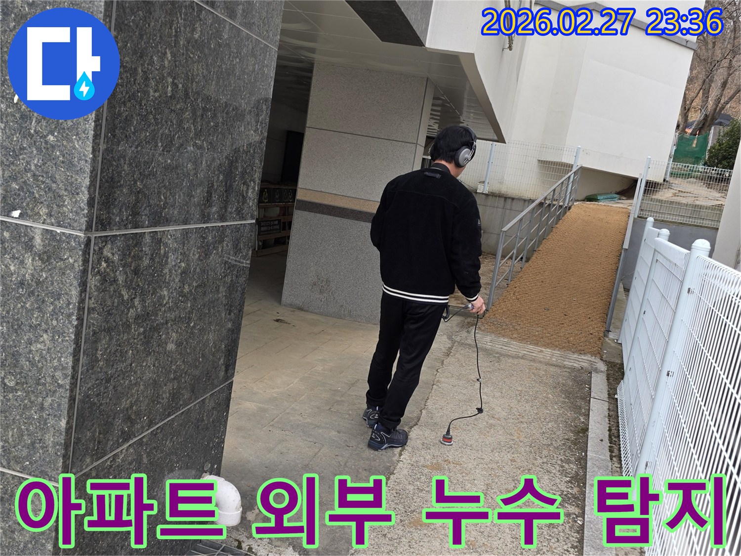 누수 엔지니어가-청음식 탐지 장비로-아파트 외부의-배관 누수 지점을 정밀하게 탐지하는 모습