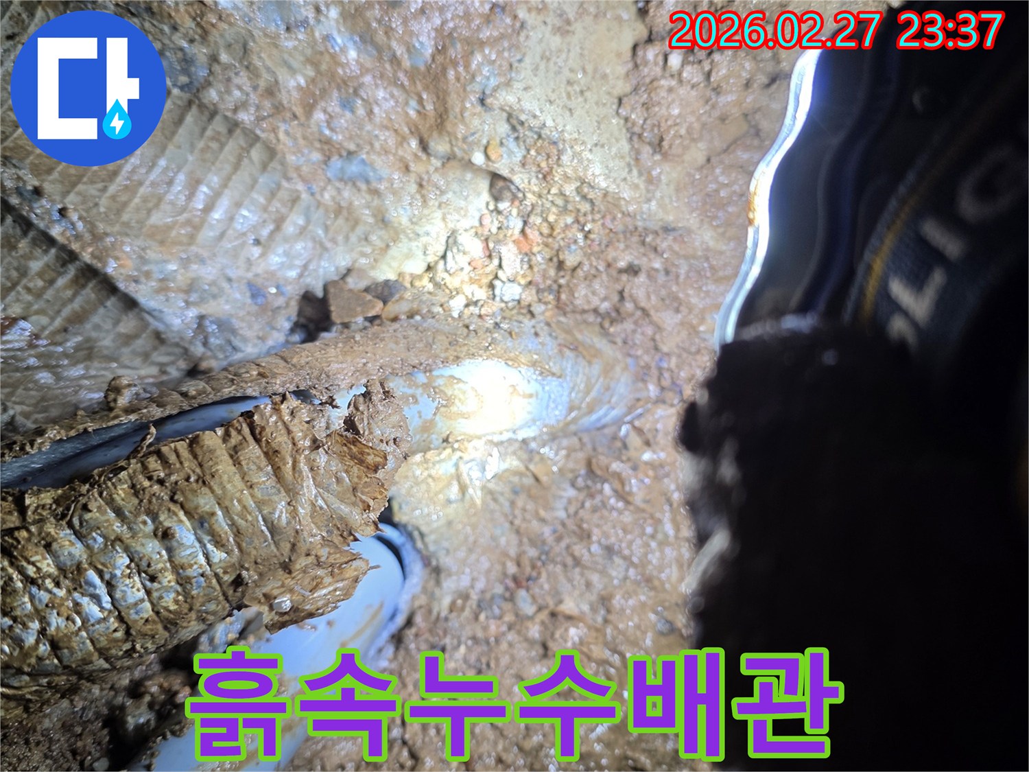 흙더미-속에서-누수가-진행-중인-배관의-손상된-부분을-확대하여-보여주는-사진