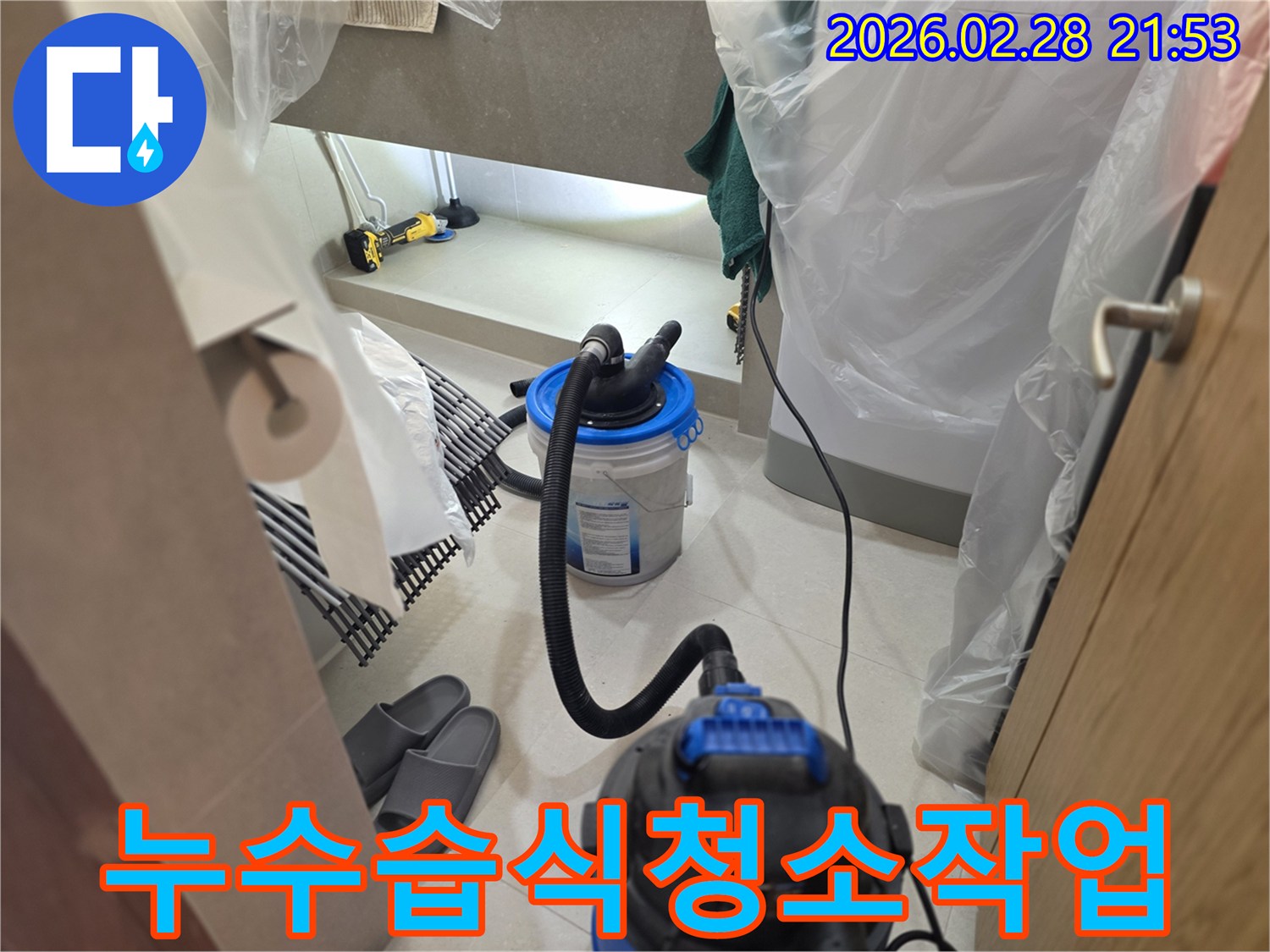 이 이미지는 누수 현장에서-주변을 비닐로 보양한 후-강력한 습식 청소기를 사용하여-고여있는 물기를 완벽하게 제거하는 작업을 보여줍니다.