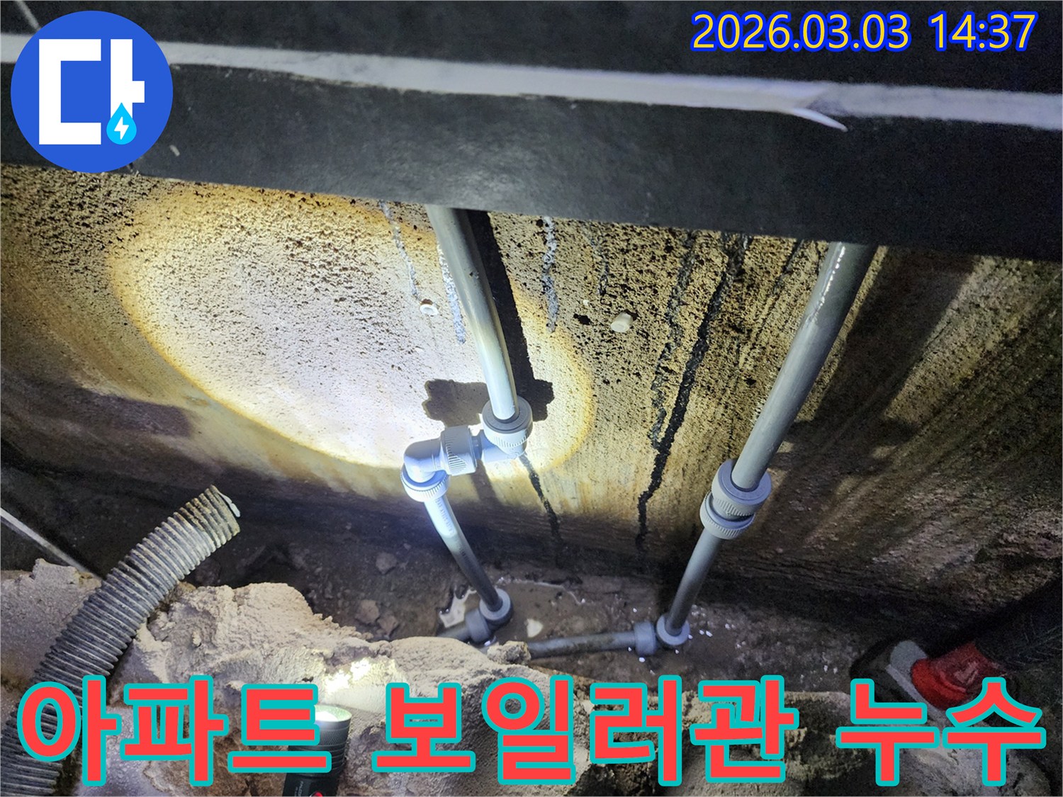어두운 보일러실에서-손전등으로 비춘-보일러 배관의-연결부 누수를-전문가가 확인하는 장면입니다.