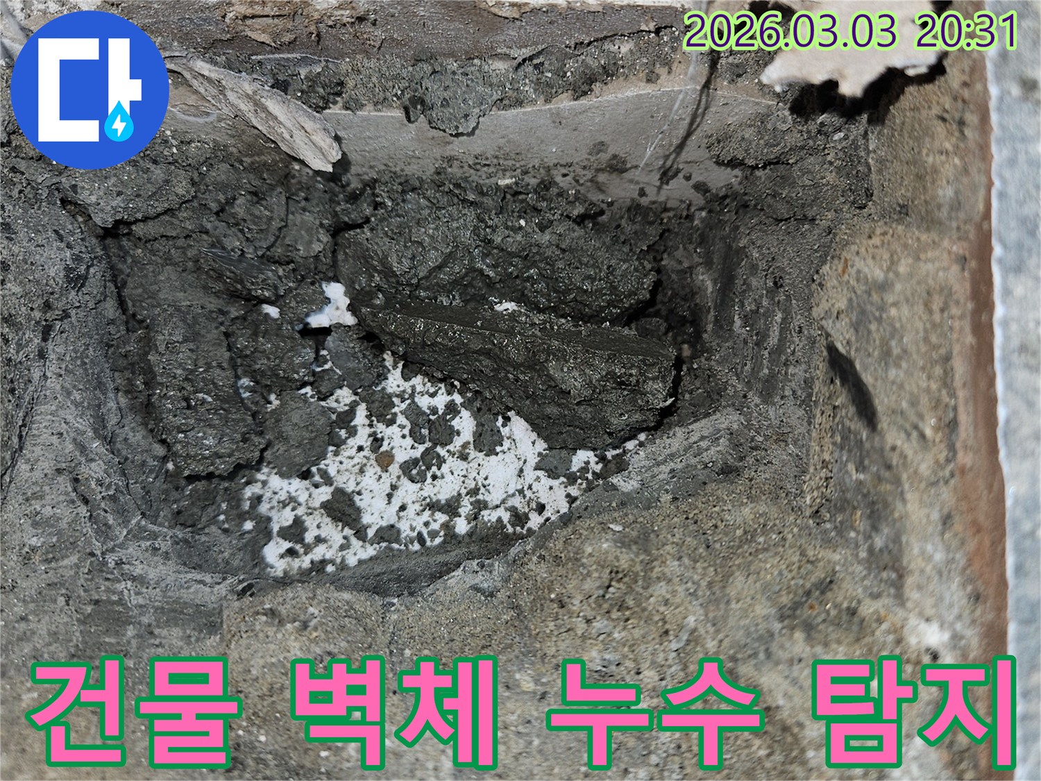건물 벽체 내부 누수 원인을 파악하기 위해 벽면을 개방하고-젖은 시멘트와 물이 스며든 흔적을 면밀히 관찰하고 있습니다.