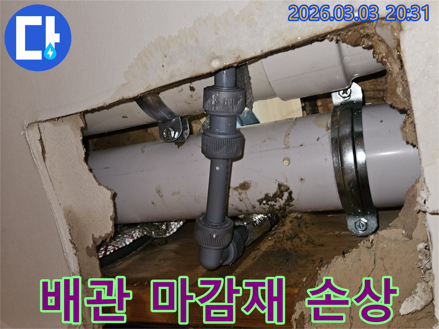 벽 안쪽 배관의 외부 마감재가 손상되어 물이 새는 모습-손상된 부위와 물기로 젖은 주변