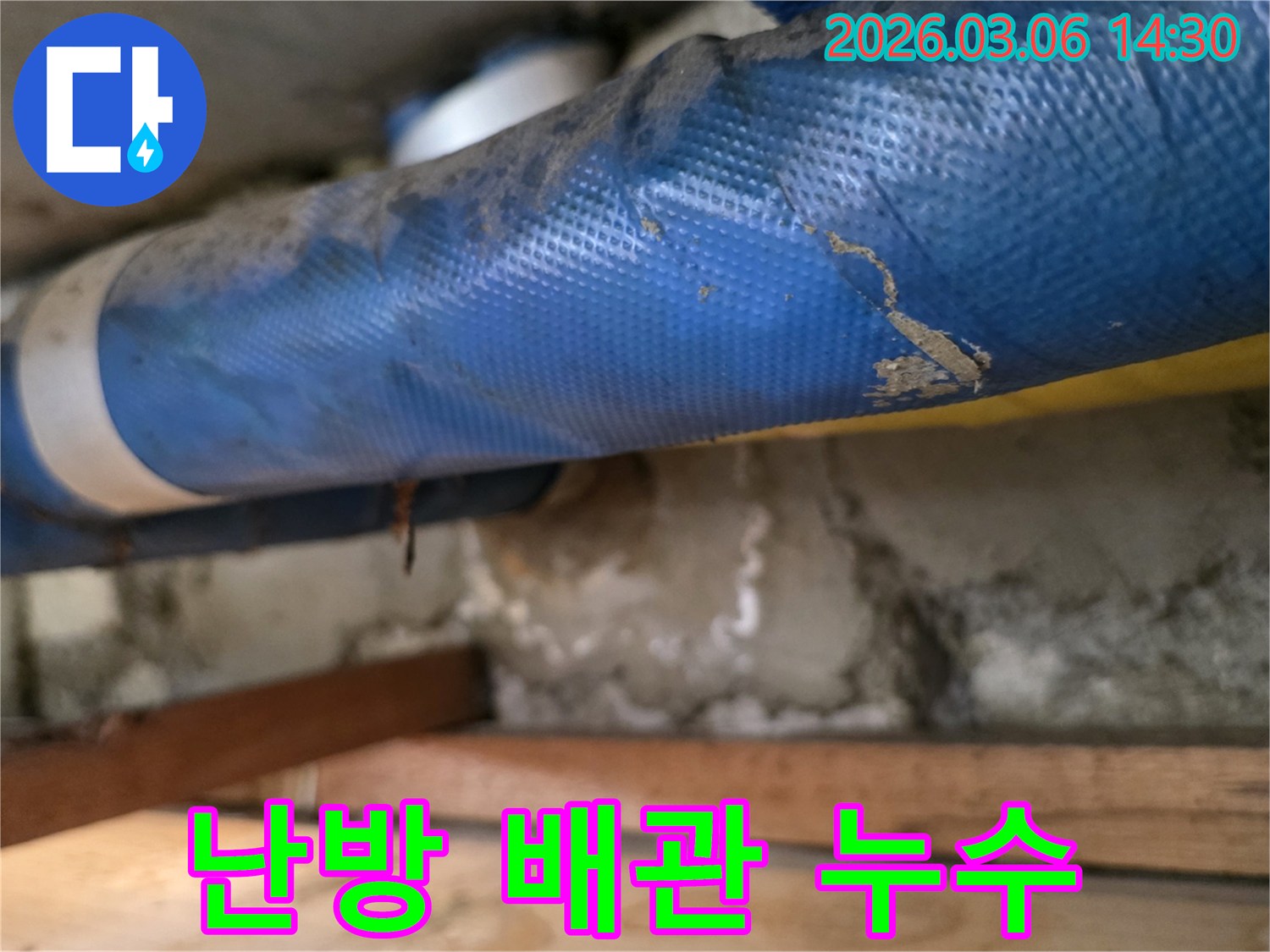 빌라 내부-파란색 난방 배관과-젖은 콘크리트 벽면-그리고 나무 지지대를-정밀하게 점검하는 모습
