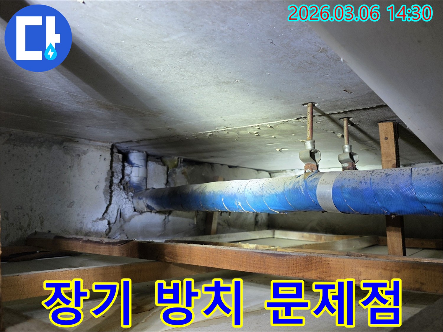 지하 공간의 파란색 배관 옆-오랜 누수로 인해-심각하게 손상된 콘크리트 벽면이-장기 방치 시의 위험성을-경고하는 현장 사진