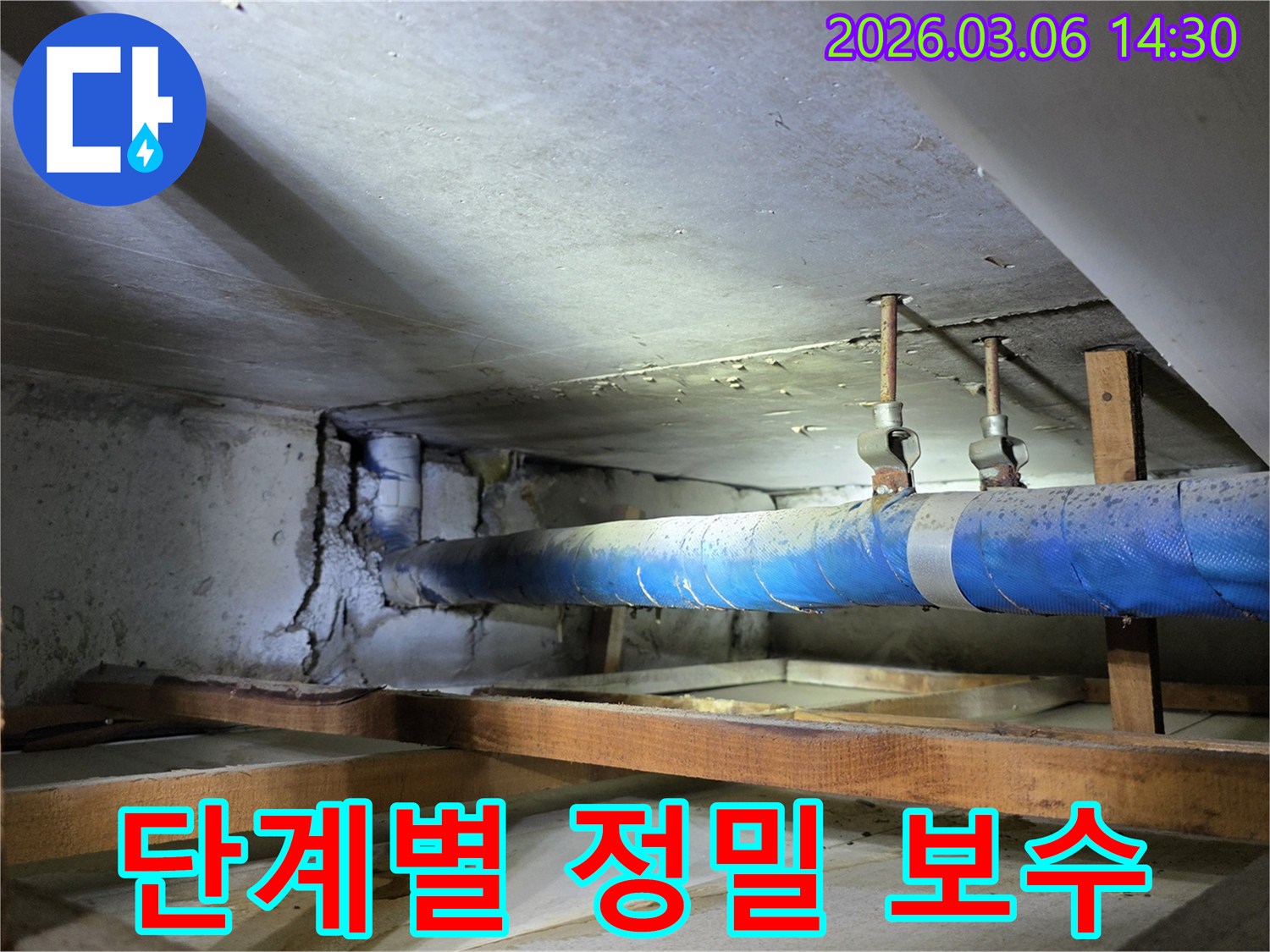 지하 공간의 파란색 배관과-손상된 콘크리트 벽면을-누수 엔지니어가-단계별 정밀 보수 공사를 위해-점검하는 모습