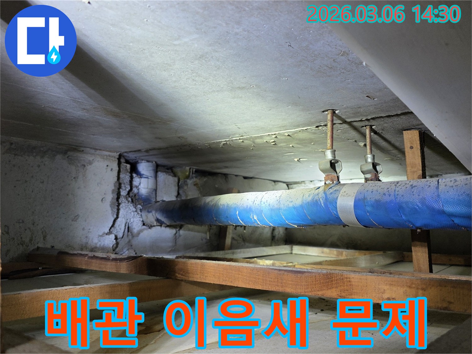 지하 공간의 파란색 배관과-손상된 콘크리트 벽면을-누수 엔지니어가-점검하며 배관 이음새 문제를-해결하기 위한 방안을 모색하는 모습