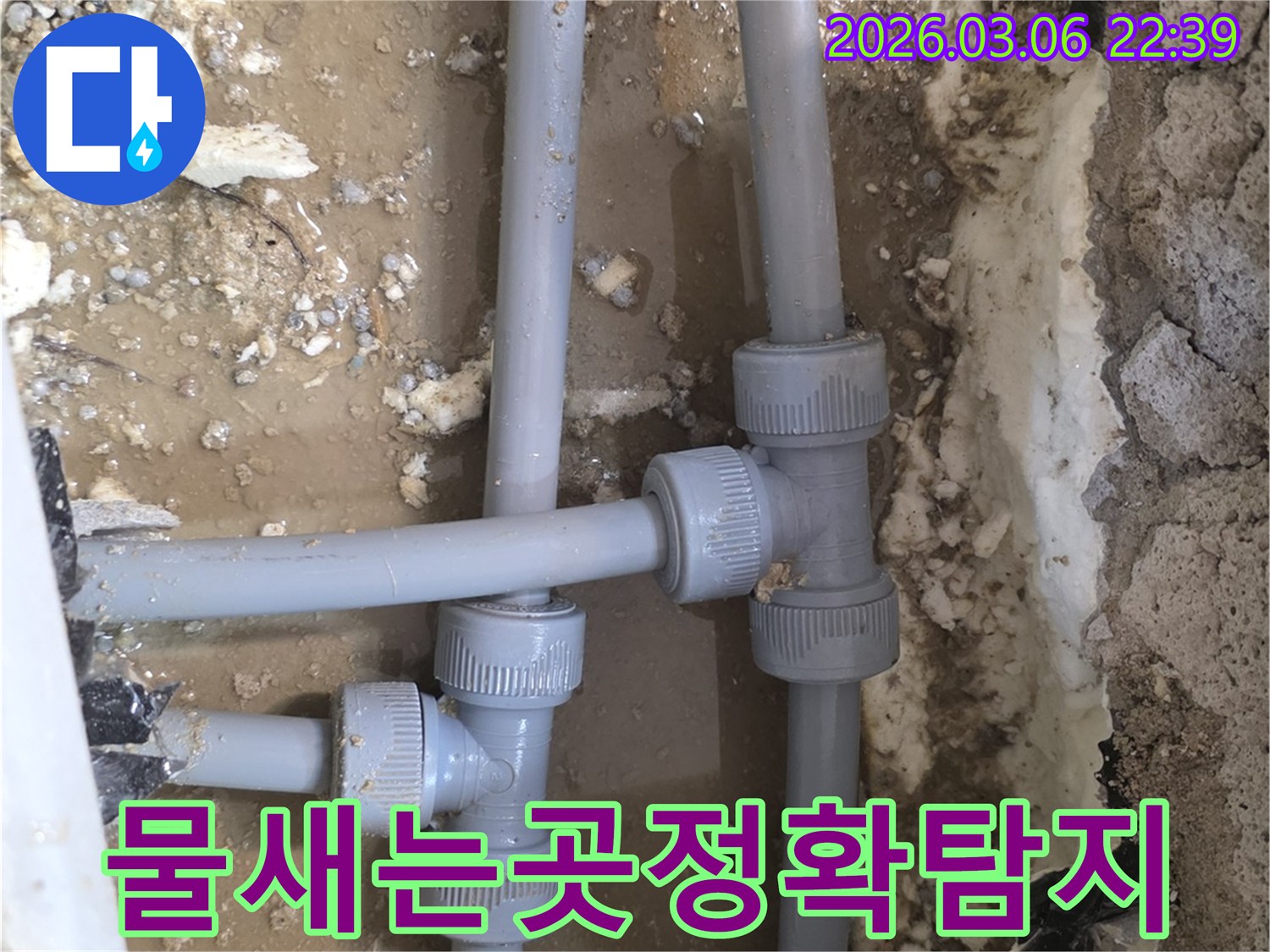 물이 새어 나오고 있는-배관의 T자 연결 부위를-가까이서 촬영하여-문제 지점을 명확히 보여줍니다