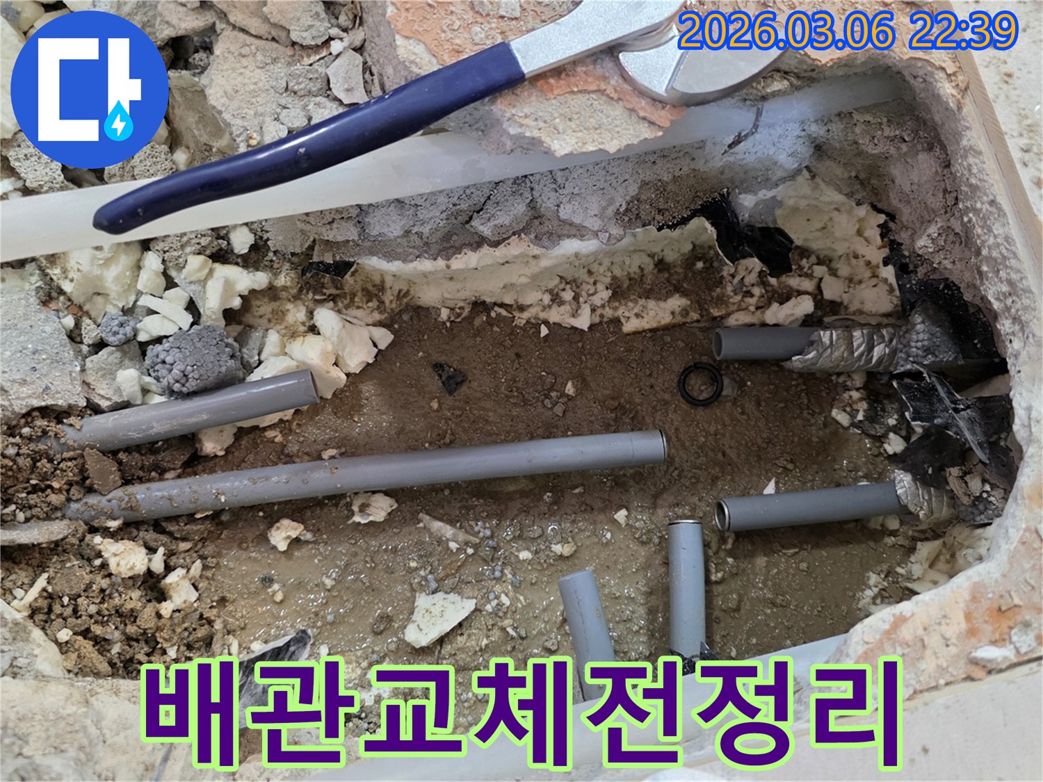 이 이미지는 누수로 인해 손상된 배관을 교체하기 위해-주변을 정리하고 새로운 배관 자재를 준비하는 공사 현장을 보여줍니다