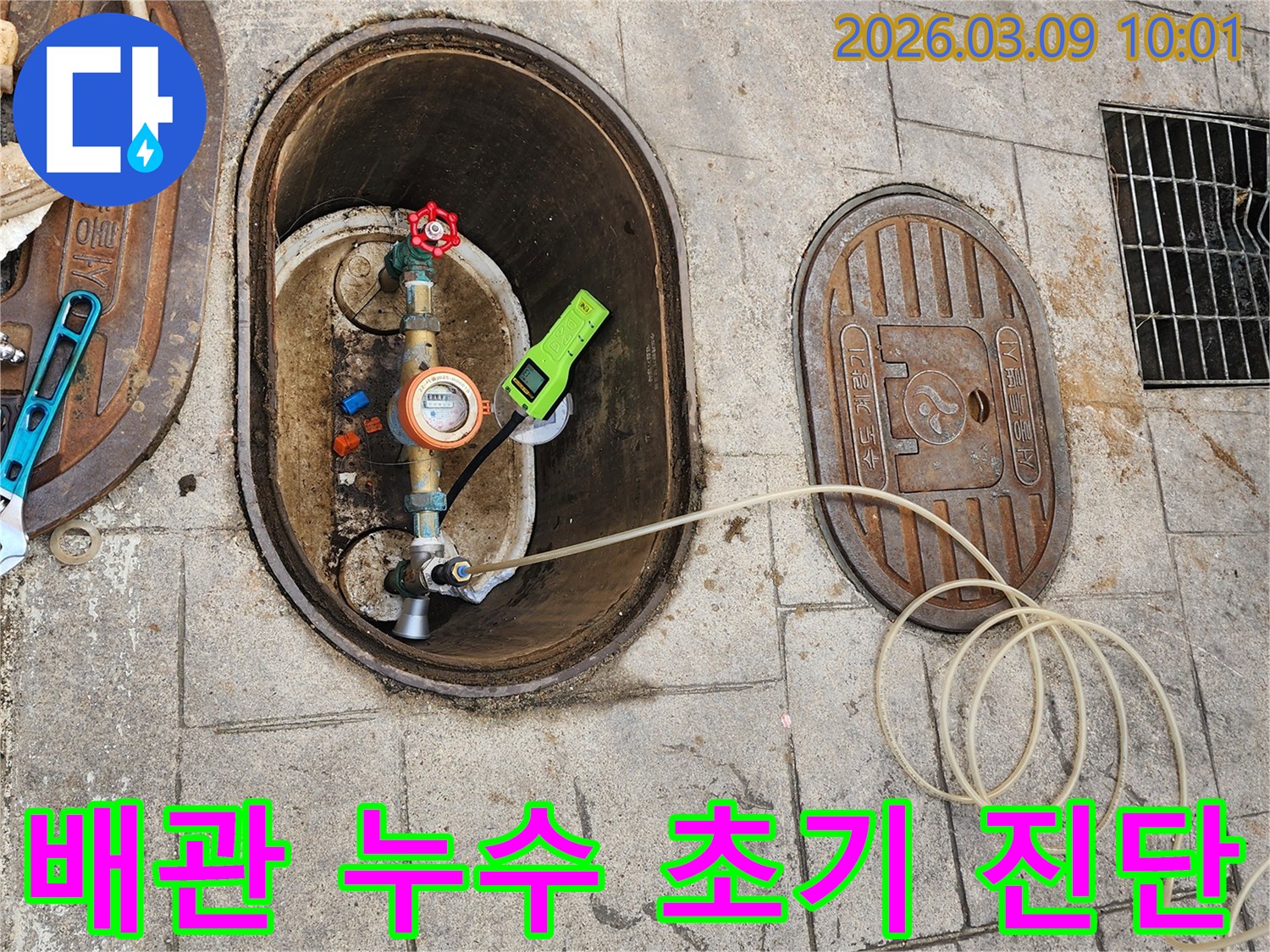 배관 누수 여부를 확인하기 위해-수도 계량기에-전문 탐지 장비를 연결하여-정밀 검사하는 모습입니다