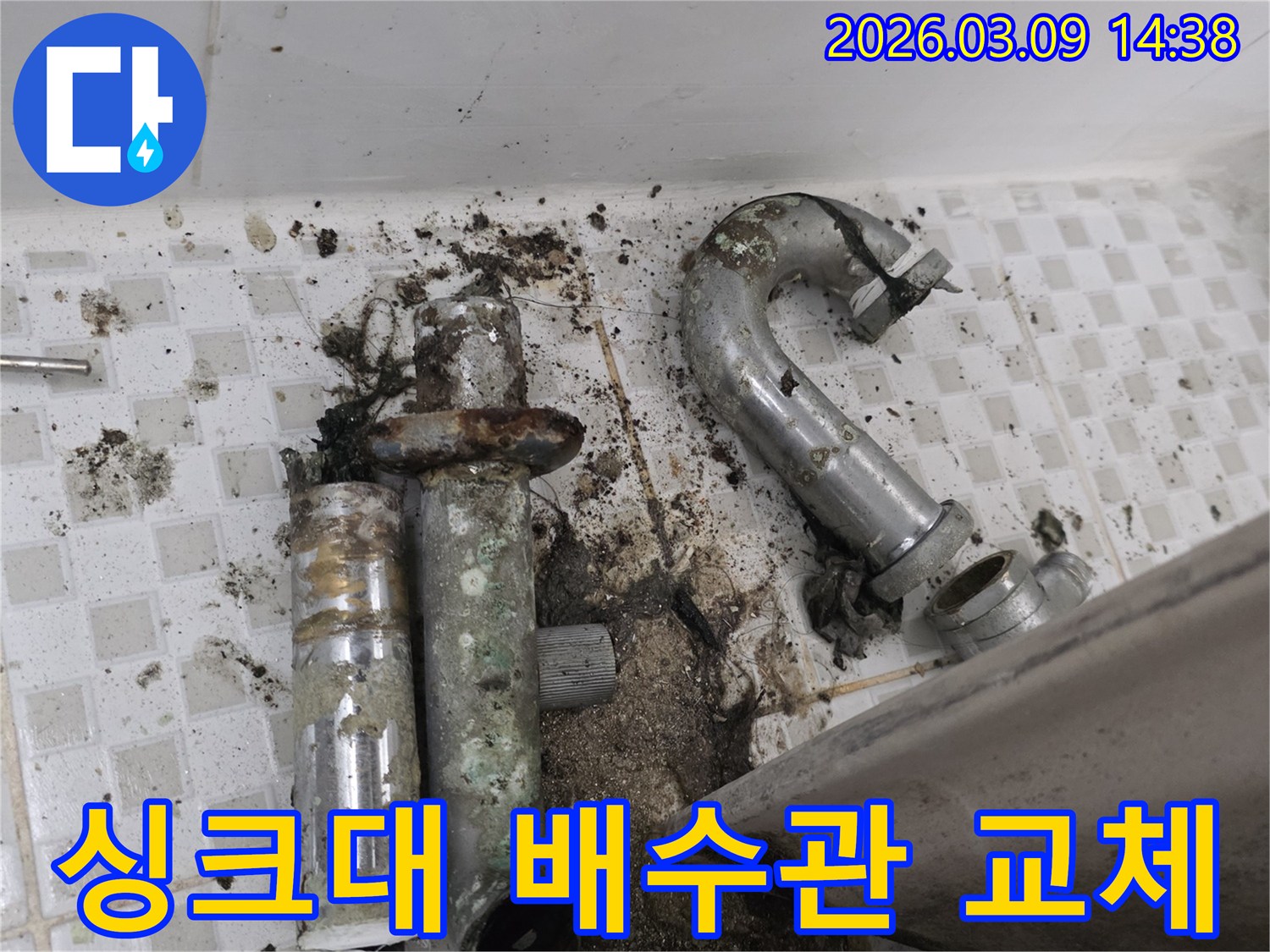 이 이미지는 공릉동 아파트 싱크대 아래-심하게 오염되고 부식된 배수관과-주변 바닥의 오염 상태를 보여줍니다-교체 전의 모습입니다